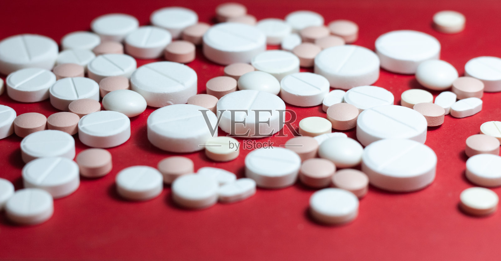 红色背景上堆着白色的药丸、药片、胶囊。药物处方用于治疗用药保健的概念与拷贝空间照片摄影图片