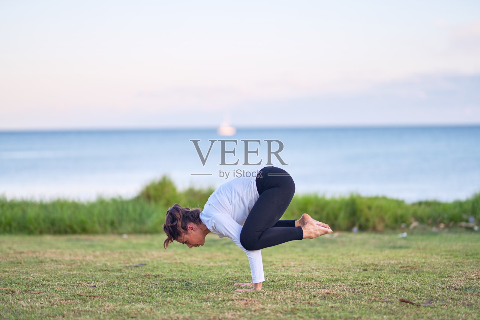 年轻漂亮的运动女性在公园练习瑜伽照片摄影图片