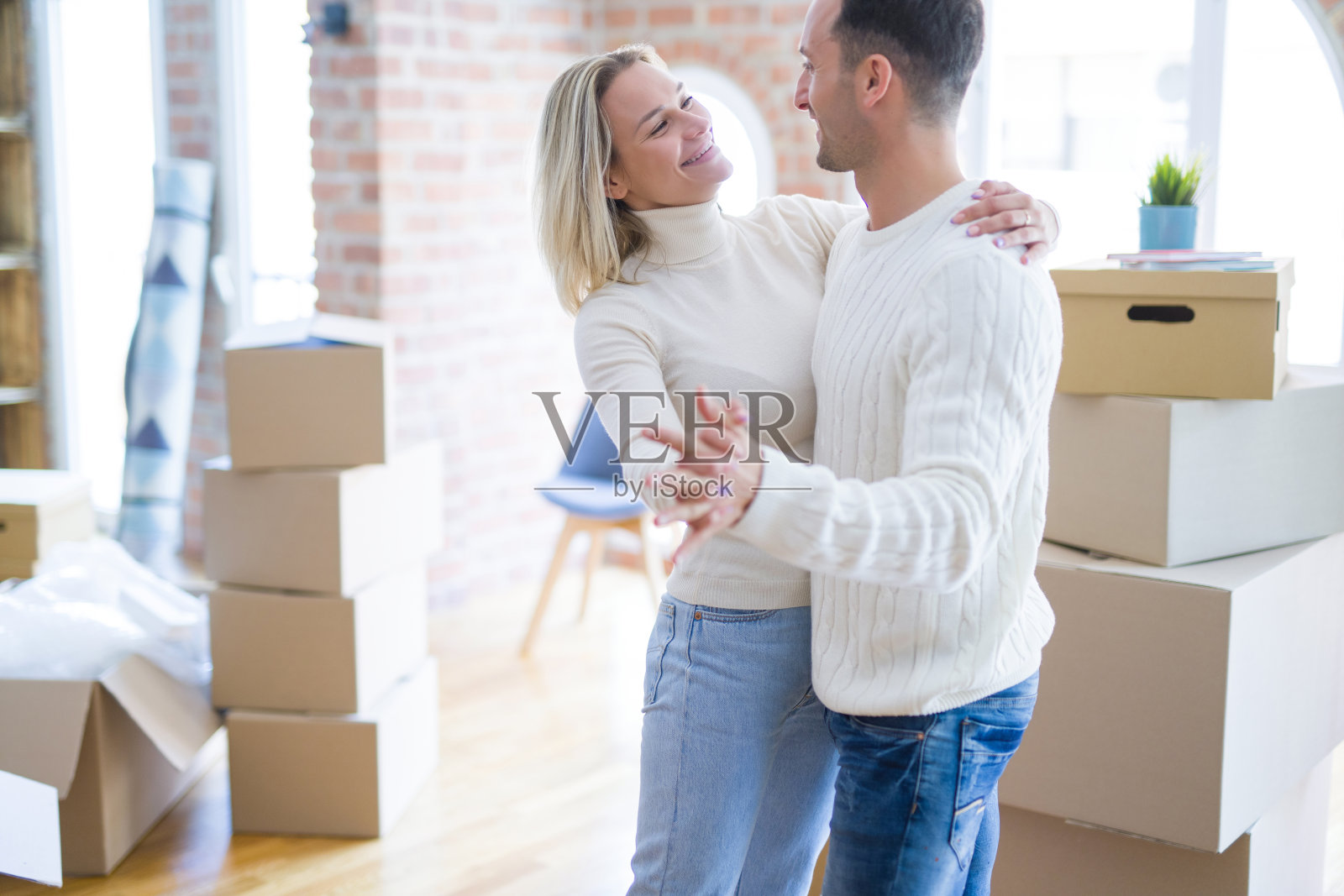 年轻漂亮的夫妇在新家里，在纸板箱旁跳舞照片摄影图片