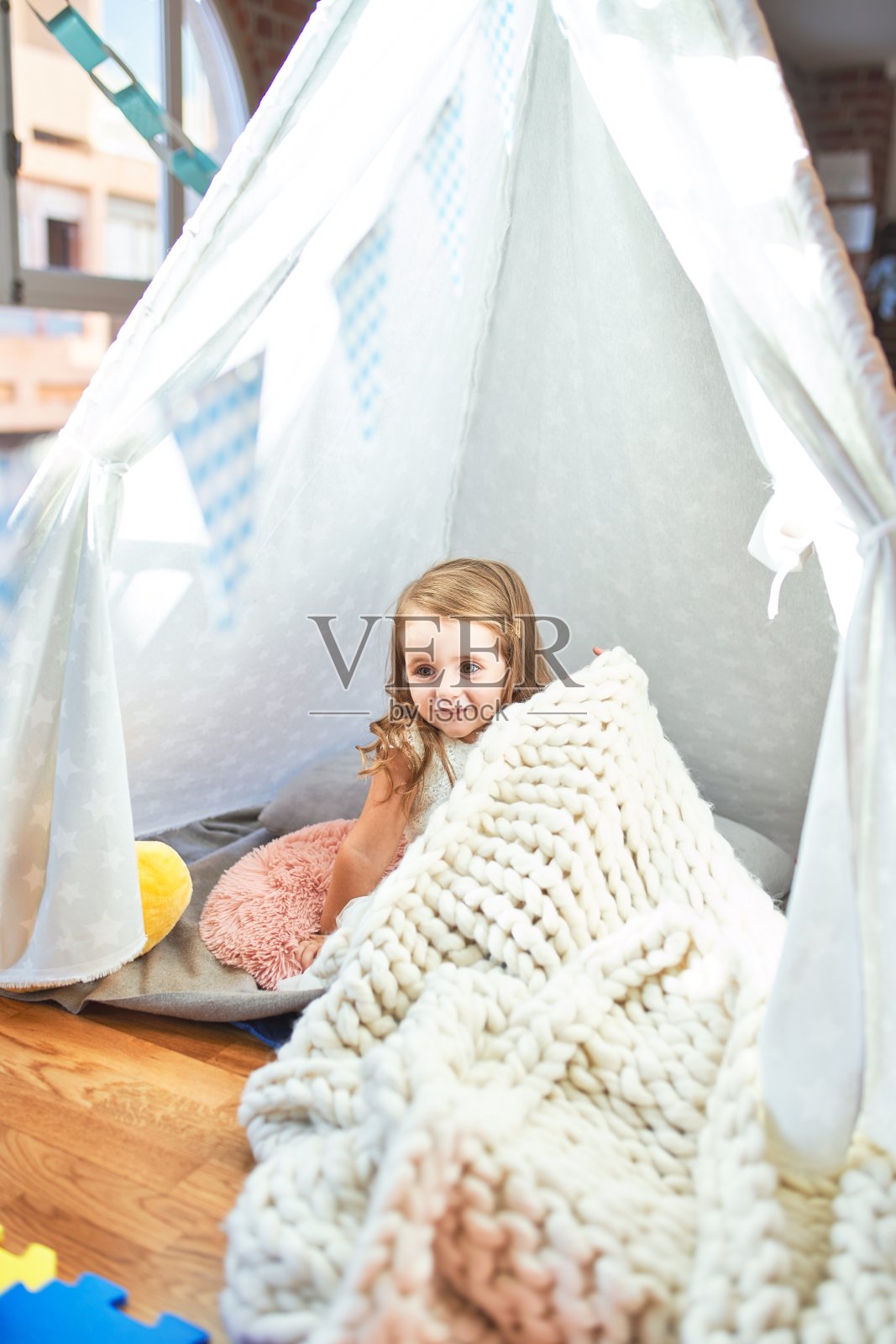 可爱的金发小孩坐在幼儿园里的毯子上玩照片摄影图片