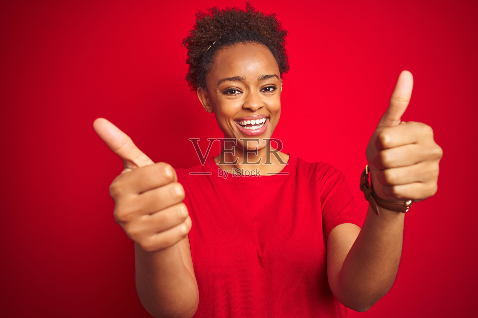 年轻漂亮的非裔美国女性，蓬松发型，竖起大拇指，为成功欢呼照片摄影图片