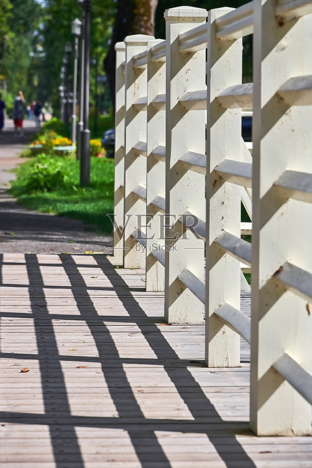 木桥的白色栏杆。桥上的栏杆在桥面上投下了一个影子。照片摄影图片