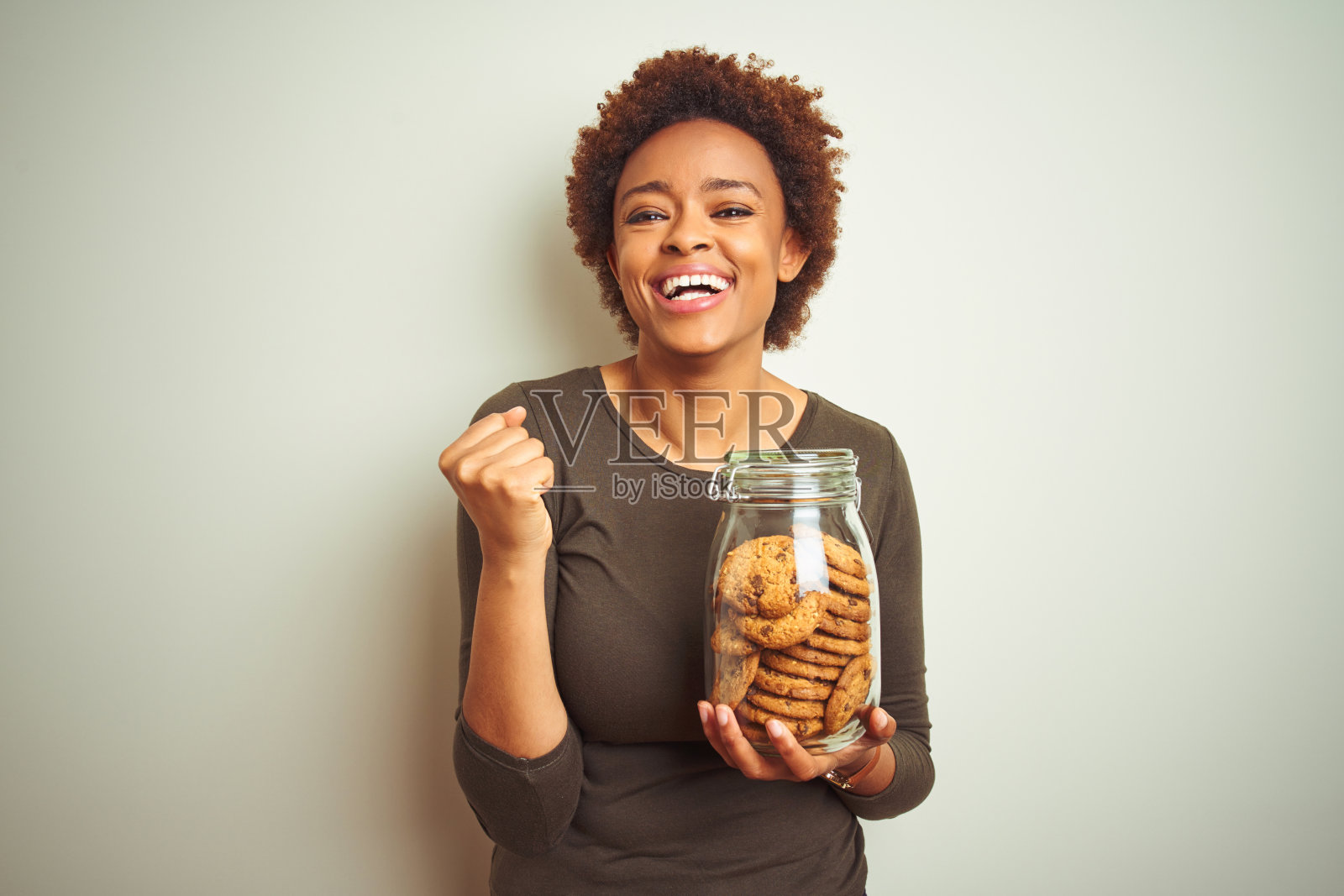 非洲裔女人拿着巧克力曲奇罐兴奋地庆祝胜利照片摄影图片