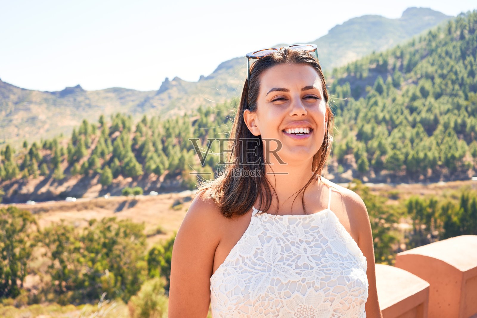 年轻美丽的女子在山上享受着暑假的风景，旅行者女孩笑得很开心照片摄影图片