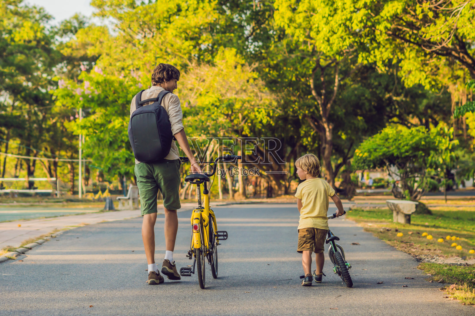 幸福家庭在户外骑自行车，父亲骑自行车，儿子骑平衡车。照片摄影图片