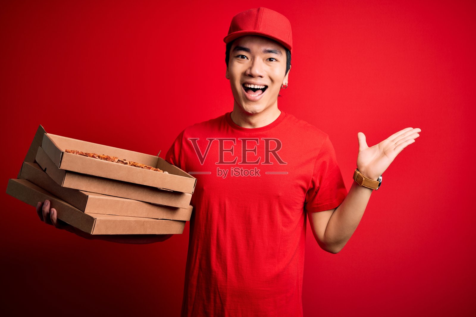 年轻帅气的中国快递员拿着装着意大利披萨的快递箱非常高兴和兴奋，胜利者的表情庆祝胜利的尖叫着，大大的微笑着举起手照片摄影图片