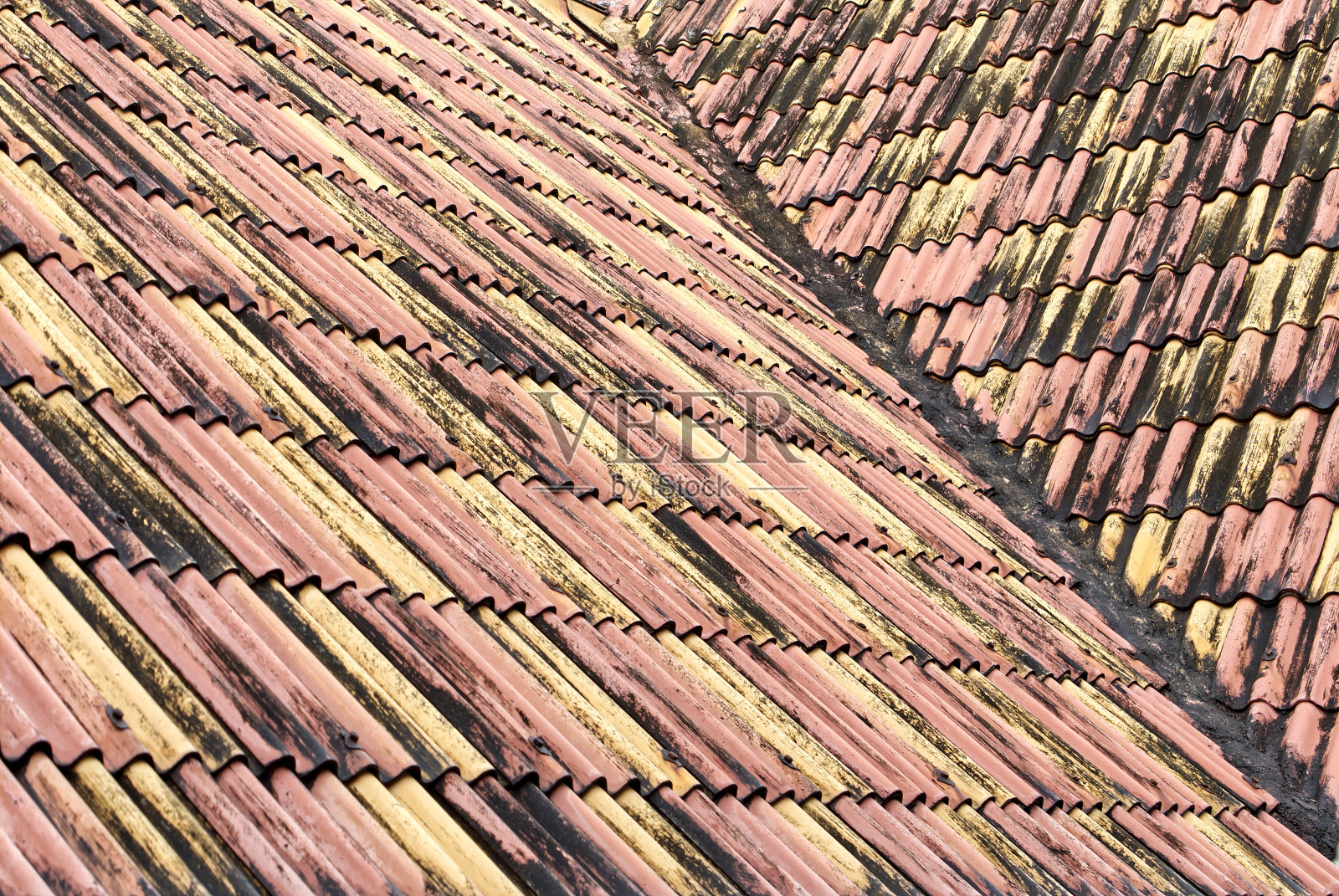 风化的旧瓦片。近距离的屋顶波浪纹理在红色和黄色的颜色。照片摄影图片