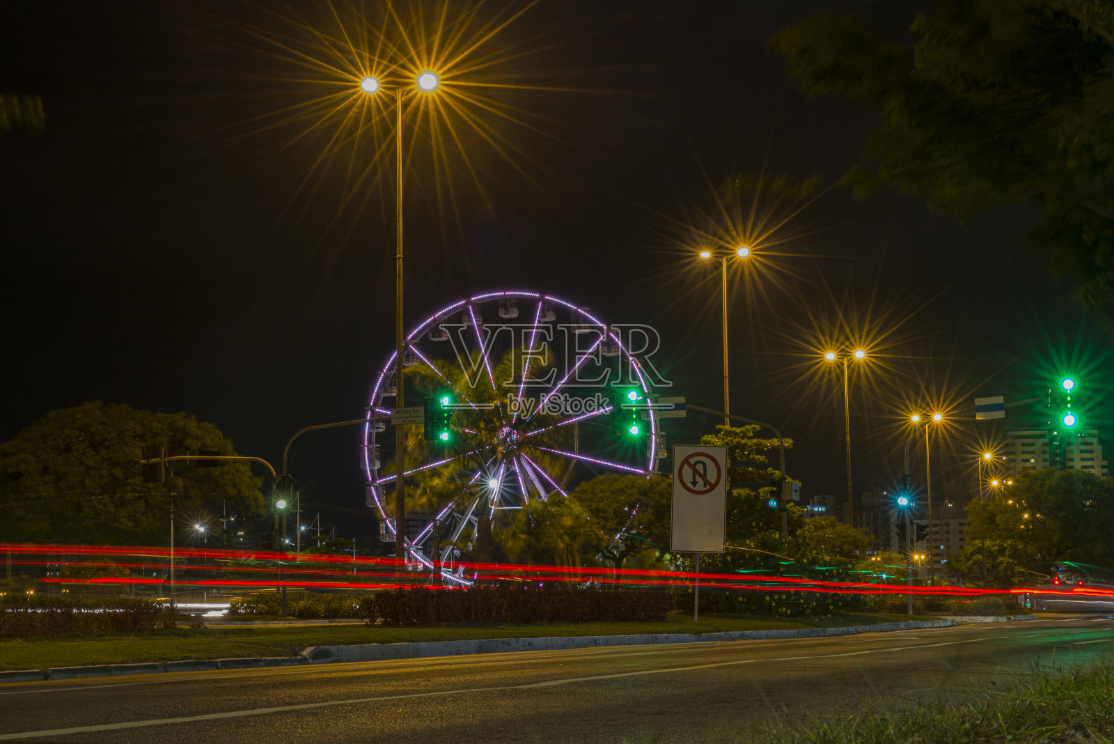 夜间高速公路上长时间曝光的五颜六色的摩天轮和灯光痕迹。照片摄影图片