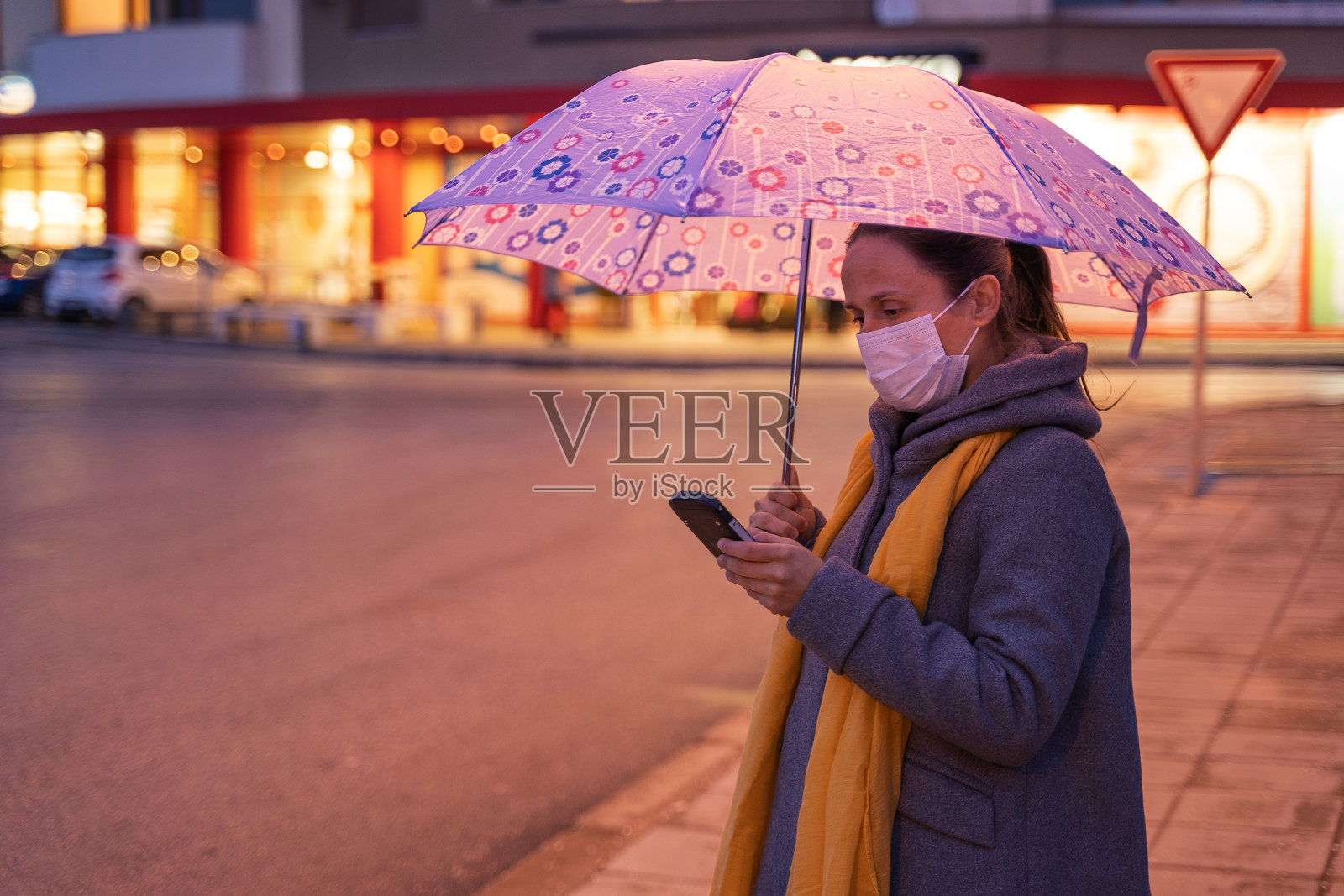 漫长工作日后在下雨城市里戴着防护口罩的年轻女人照片摄影图片