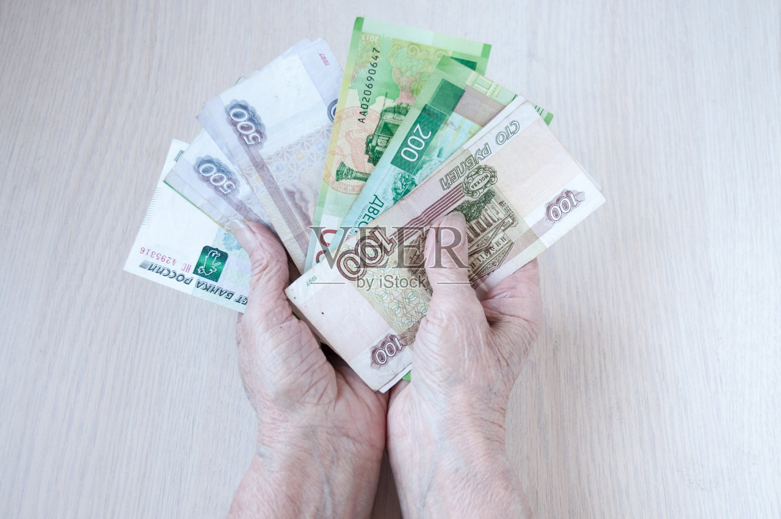 老妇人的手把俄罗斯钱放在桌子上。养老金的概念照片摄影图片