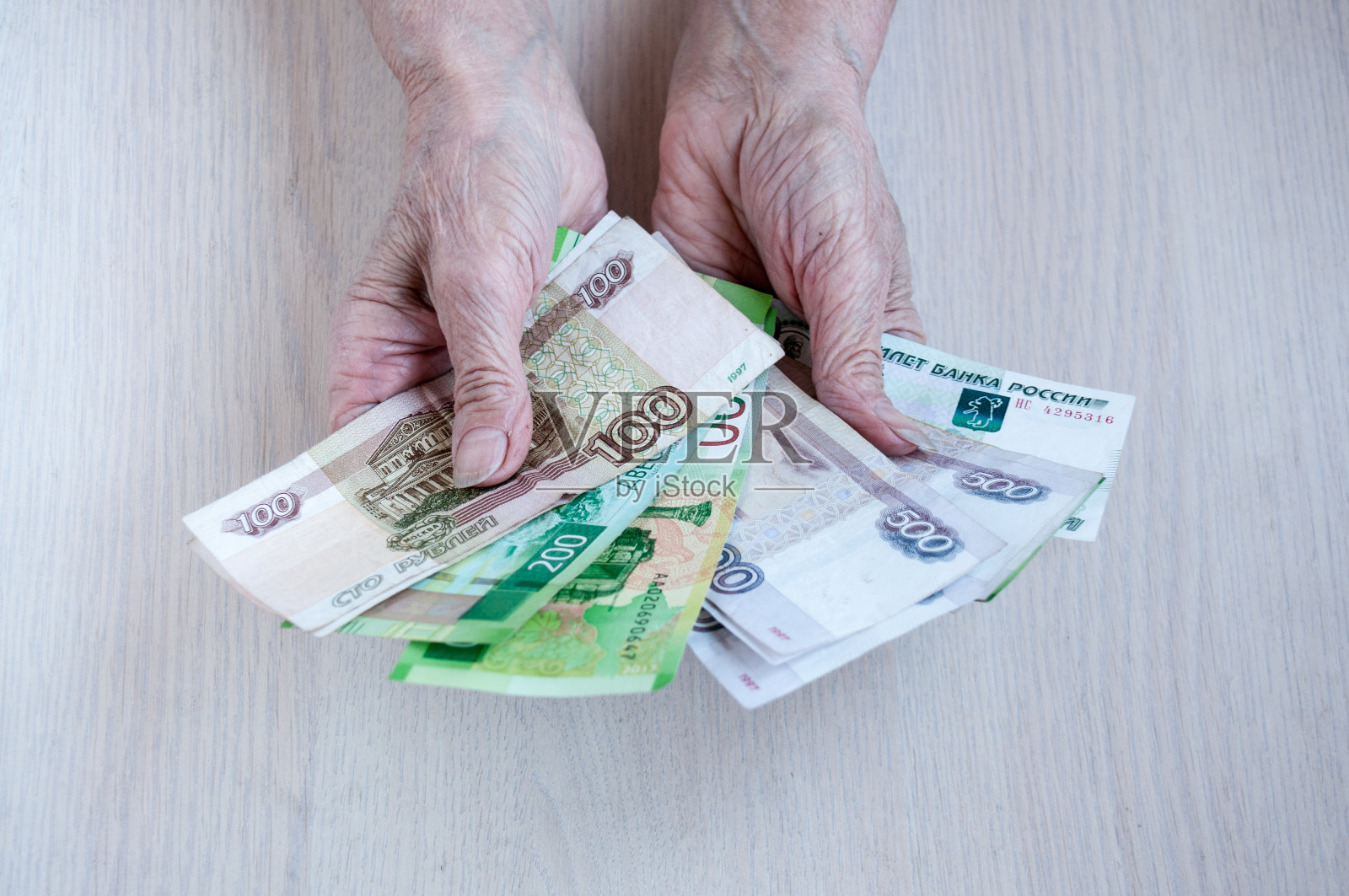 老妇人的手把俄罗斯钱放在桌子上。养老金的概念照片摄影图片