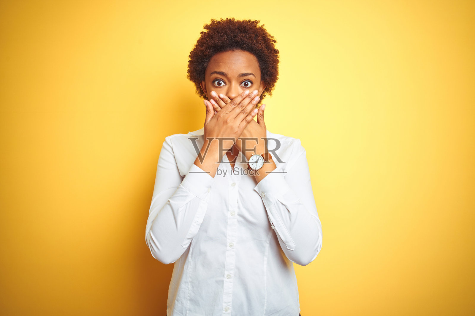 在黄色背景下，因犯错而捂住嘴巴的震惊非洲裔美国女商人照片摄影图片