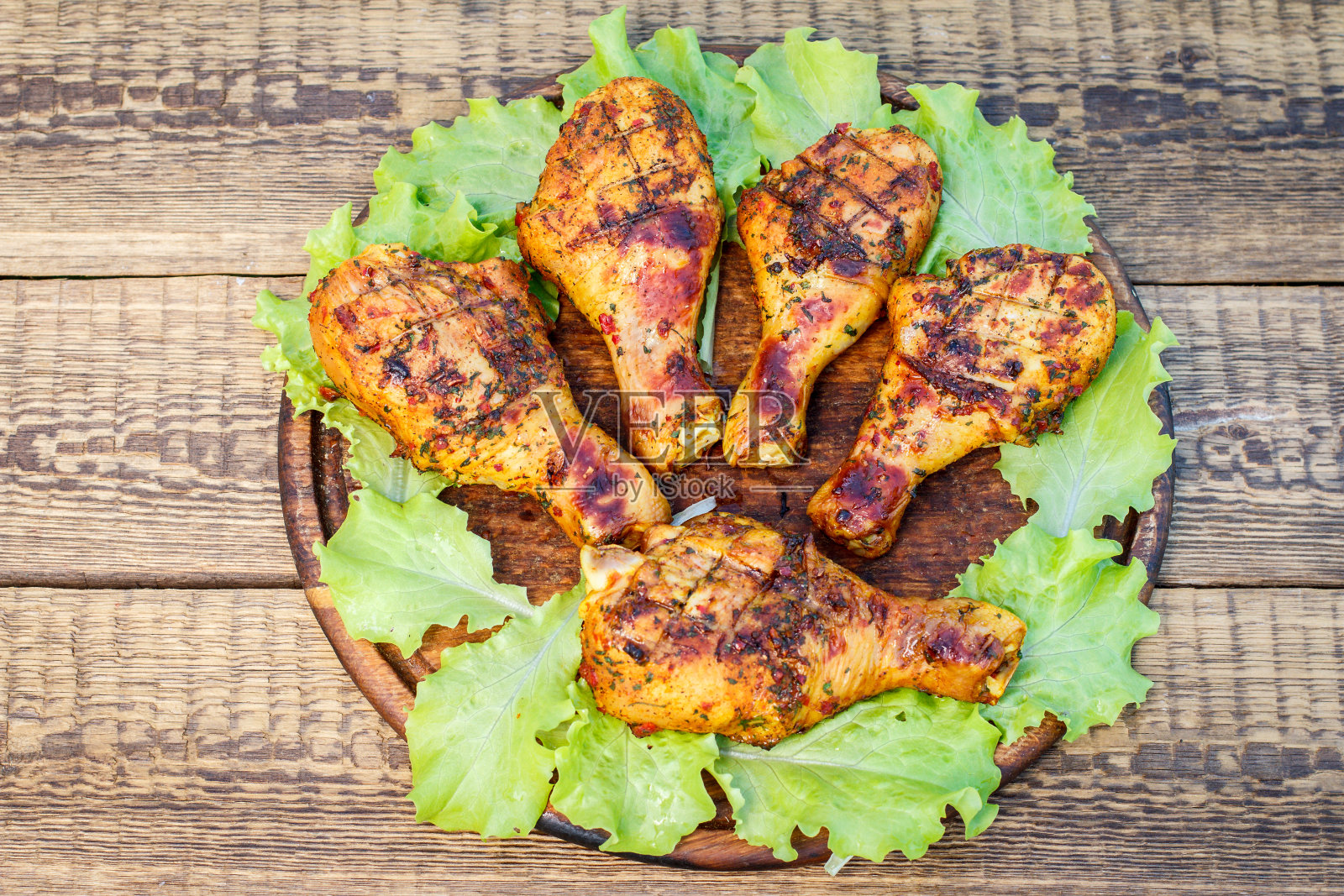 烤鸡腿和莴苣叶放在木板上照片摄影图片
