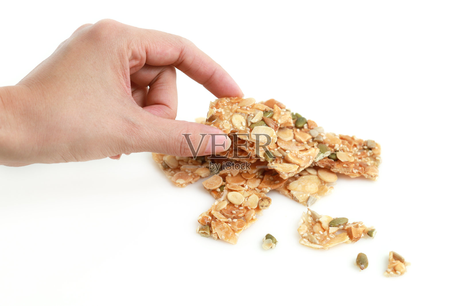 靠近女性的手拿着一块杏仁和坚果幻灯片上的白色背景饼干照片摄影图片