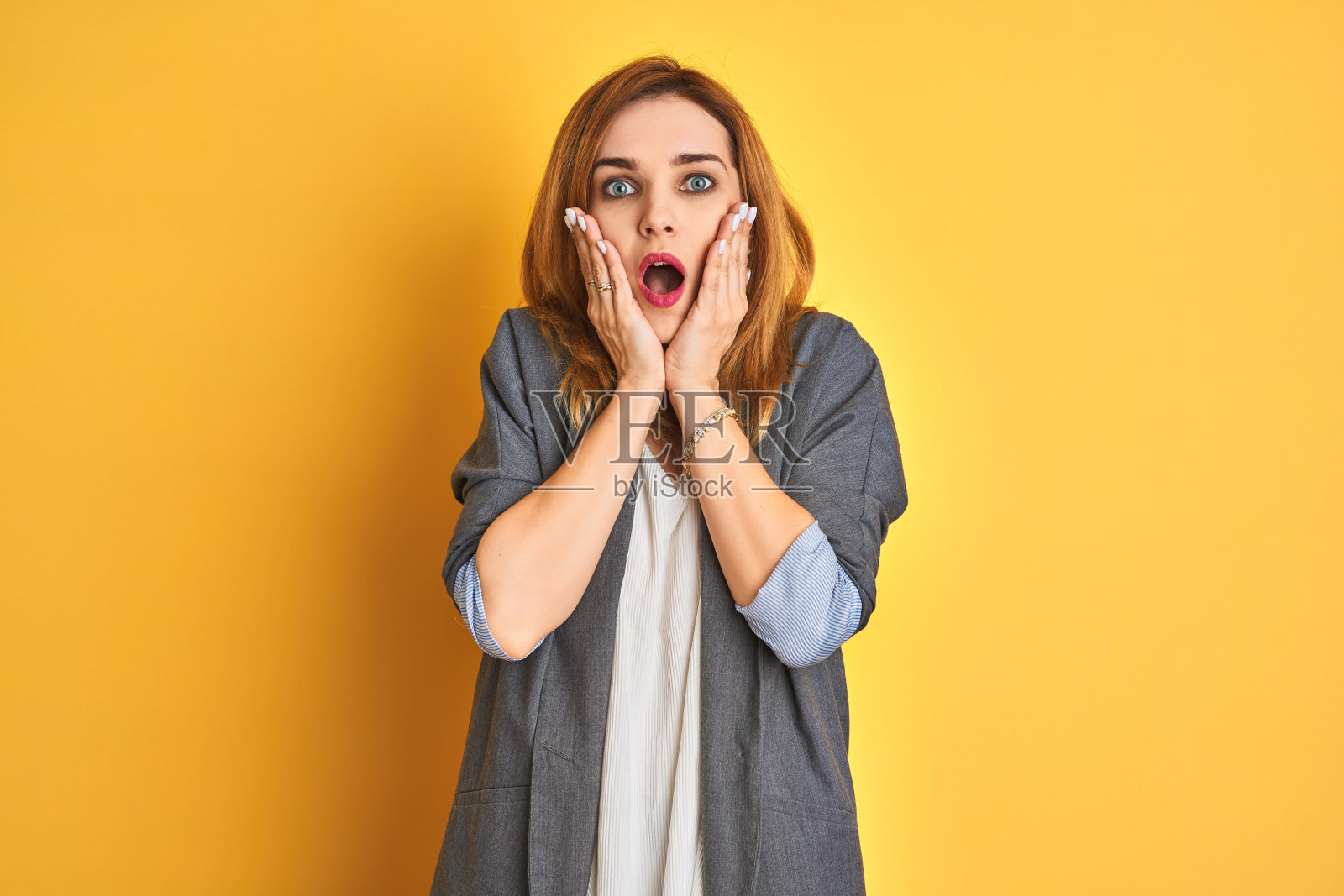 在黄色背景下，吃惊的红发白人女商人照片摄影图片