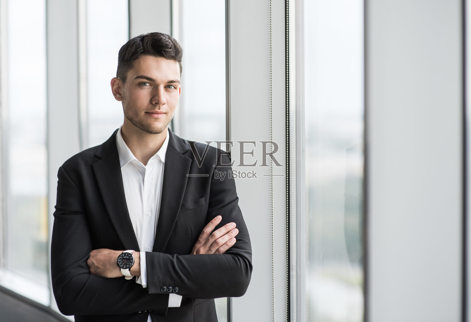 年轻商人的肖像双臂交叉在办公室照片摄影图片