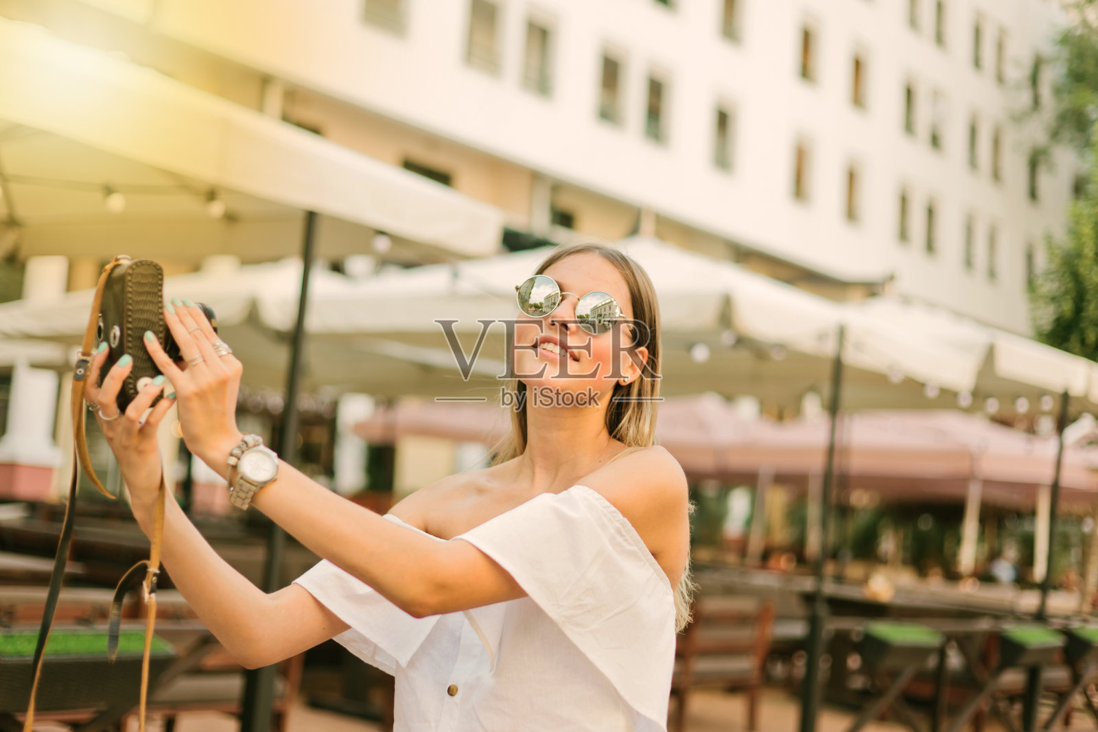 戴墨镜的快乐时尚女性在城市环境中用复古相机自拍照片摄影图片