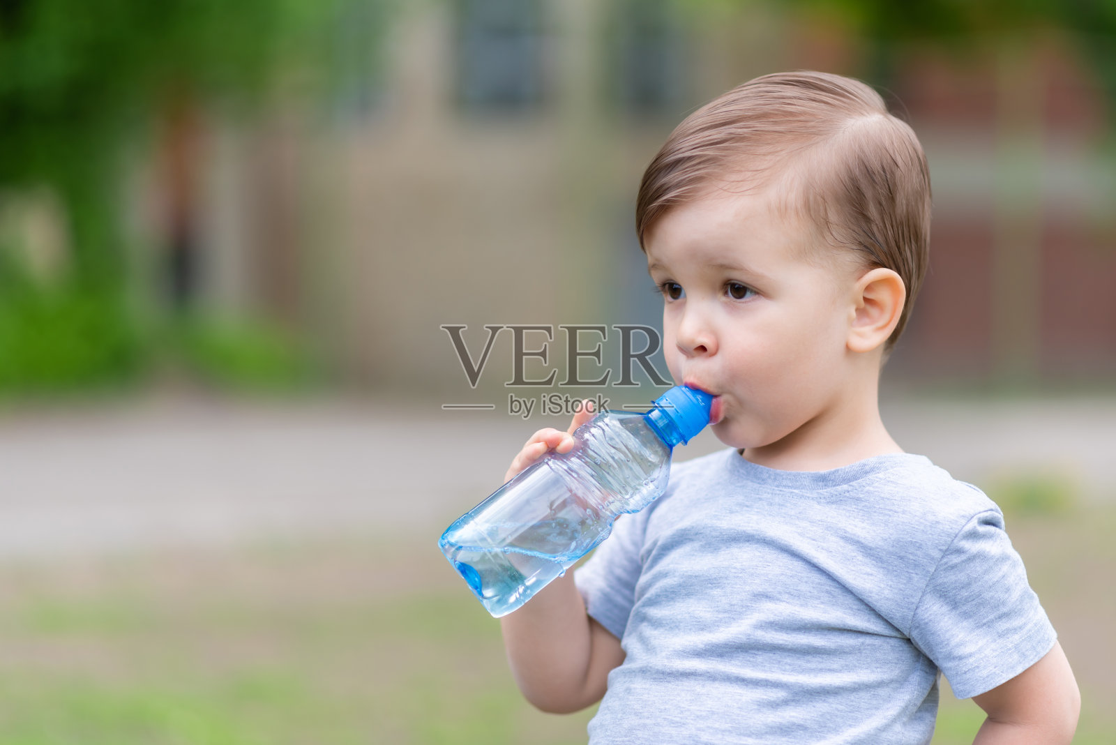 在炎热的夏天，孩子们从瓶子里喝水照片摄影图片