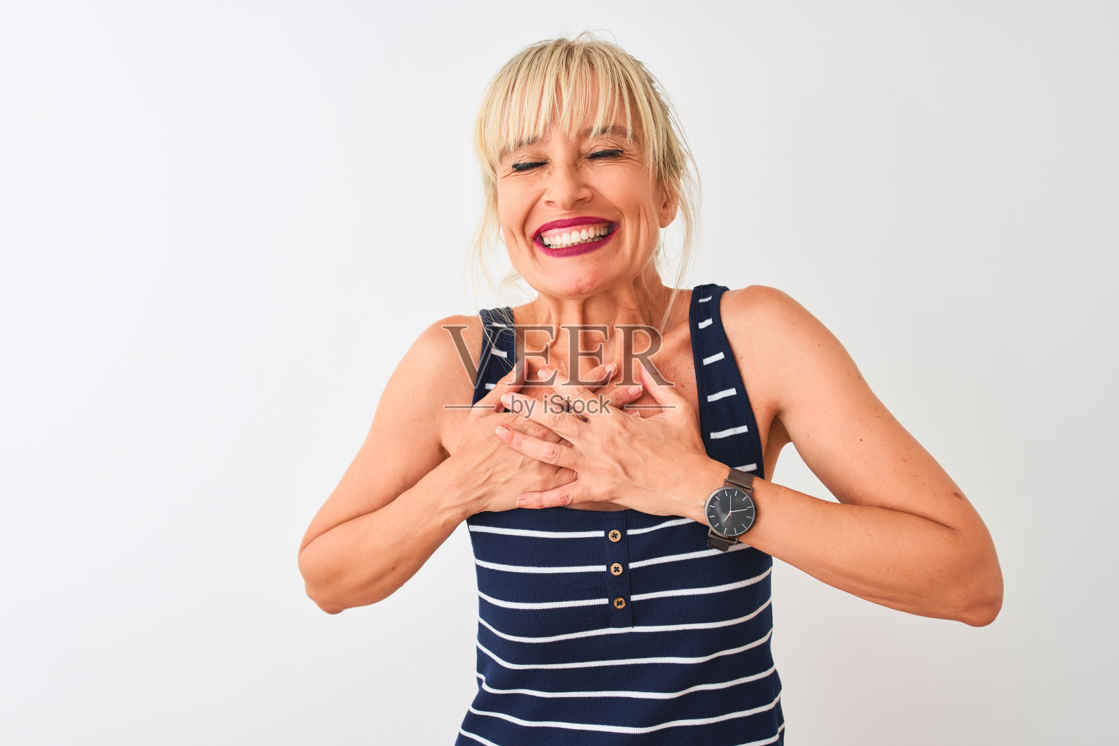 身穿休闲条纹T恤的中年妇女，在白色背景前双手合十，面带微笑，表达感激之情，健康概念照片摄影图片