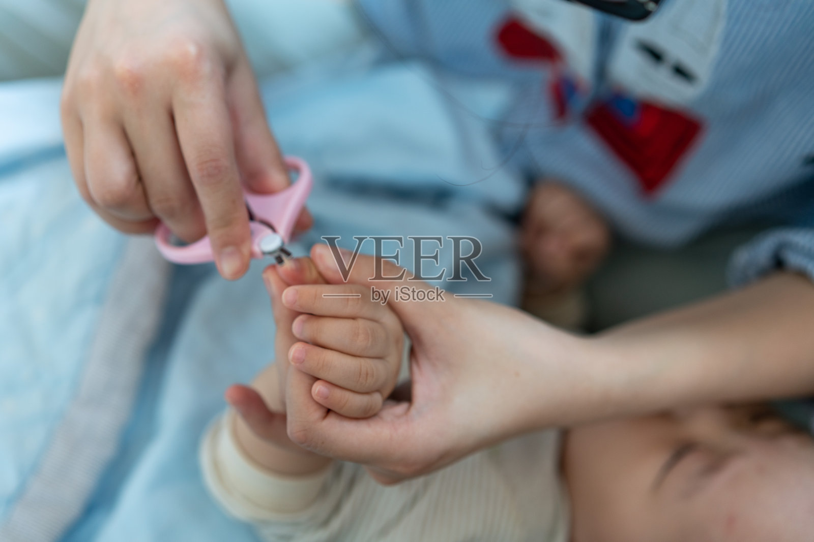 一位母亲为熟睡的孩子剪指甲照片摄影图片