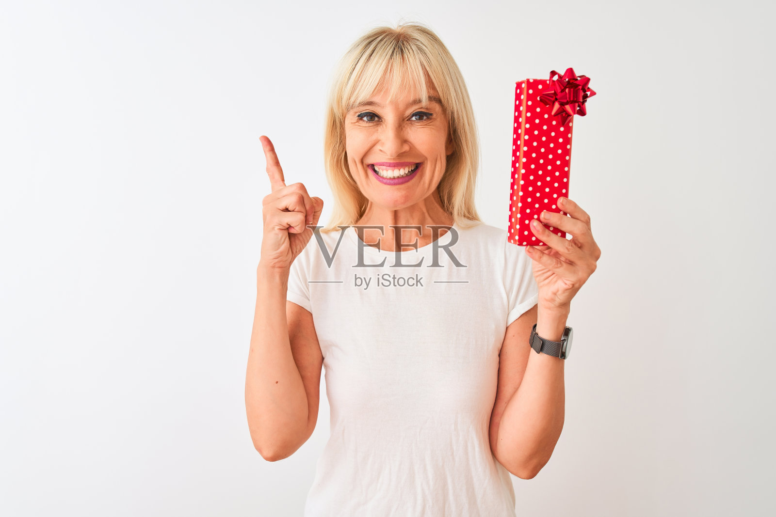 中年女人拿着情人节礼物，面带微笑地指着，表达想法或疑问，比出第一的手势照片摄影图片