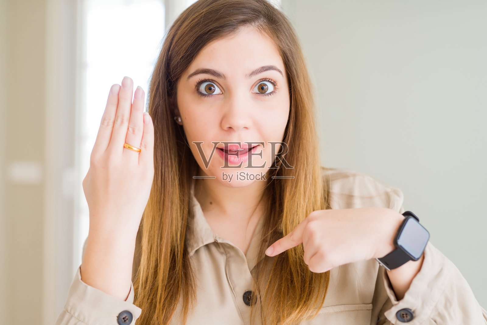 惊讶的年轻女子展示手上的戒指，并用手指指向自己照片摄影图片