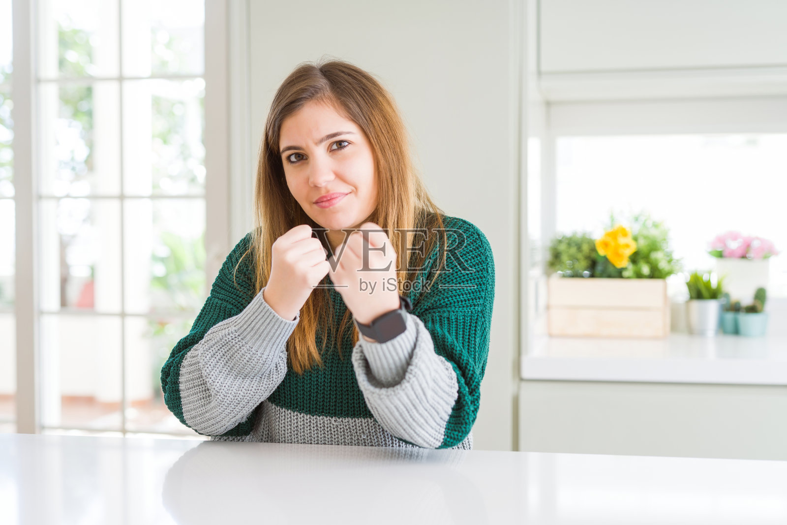 年轻漂亮的加大码女士穿着休闲条纹毛衣，握紧拳头准备战斗，面带怒色，害怕问题照片摄影图片