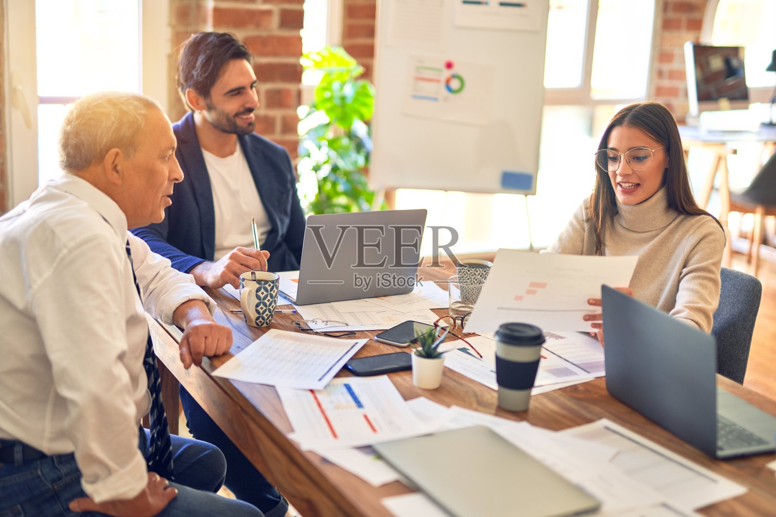 商务员工一起工作，坐在办公桌前使用笔记本电脑阅读文件照片摄影图片