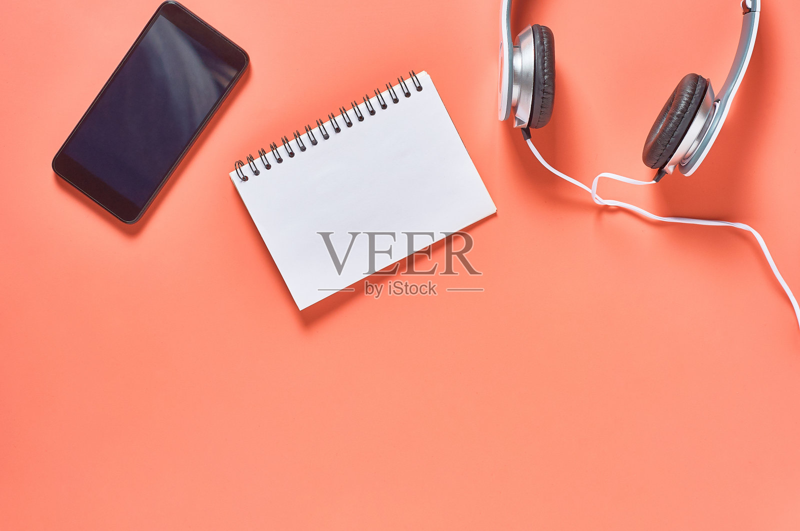 现代白色耳机，线靠近智能手机或平板电脑和空白纸记事本在橙色背景。呼叫中心的概念。副本的空间。俯视图照片摄影图片
