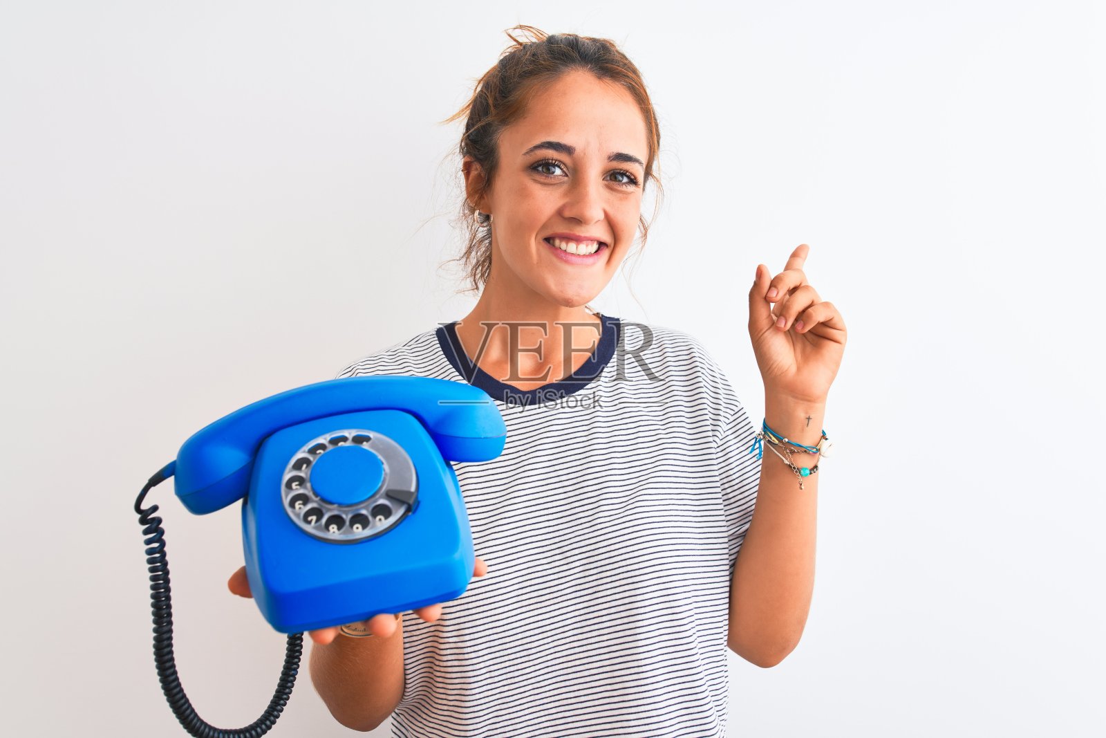 年轻的红发女人拿着经典复古电话在孤立的背景非常幸福的指向与手和手指的一边照片摄影图片