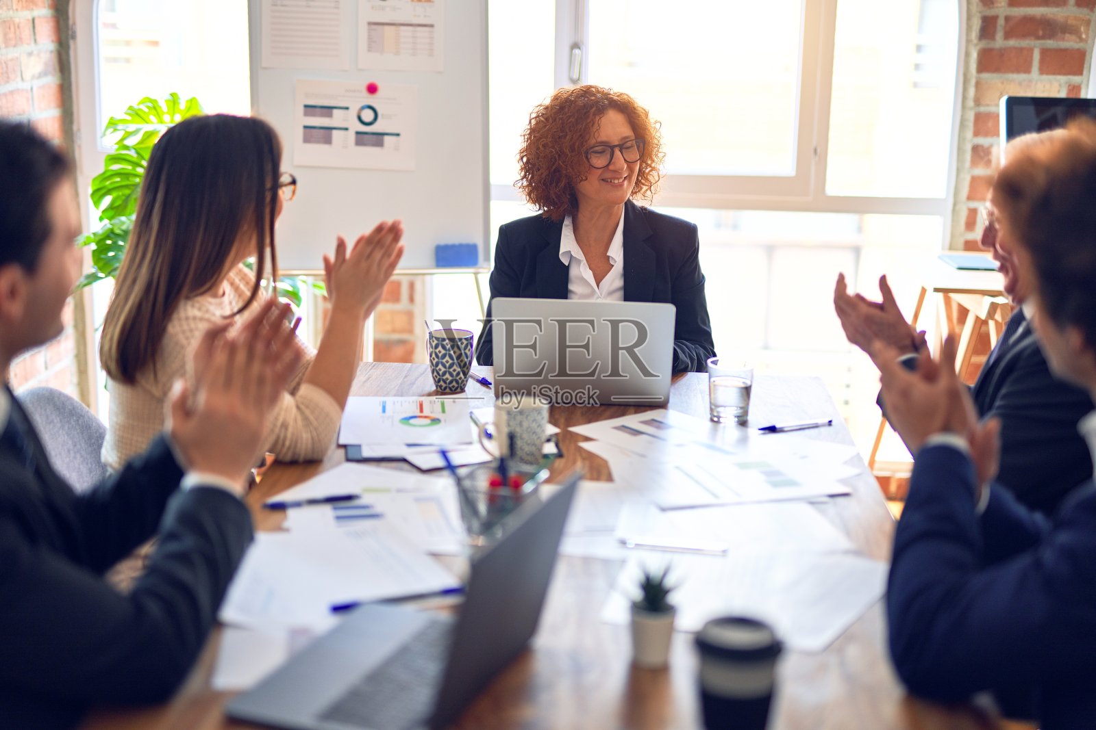 一群商务人员在会议中微笑，快乐和自信。一起看演示文稿，用板和笔记本电脑，在办公室鼓掌。照片摄影图片