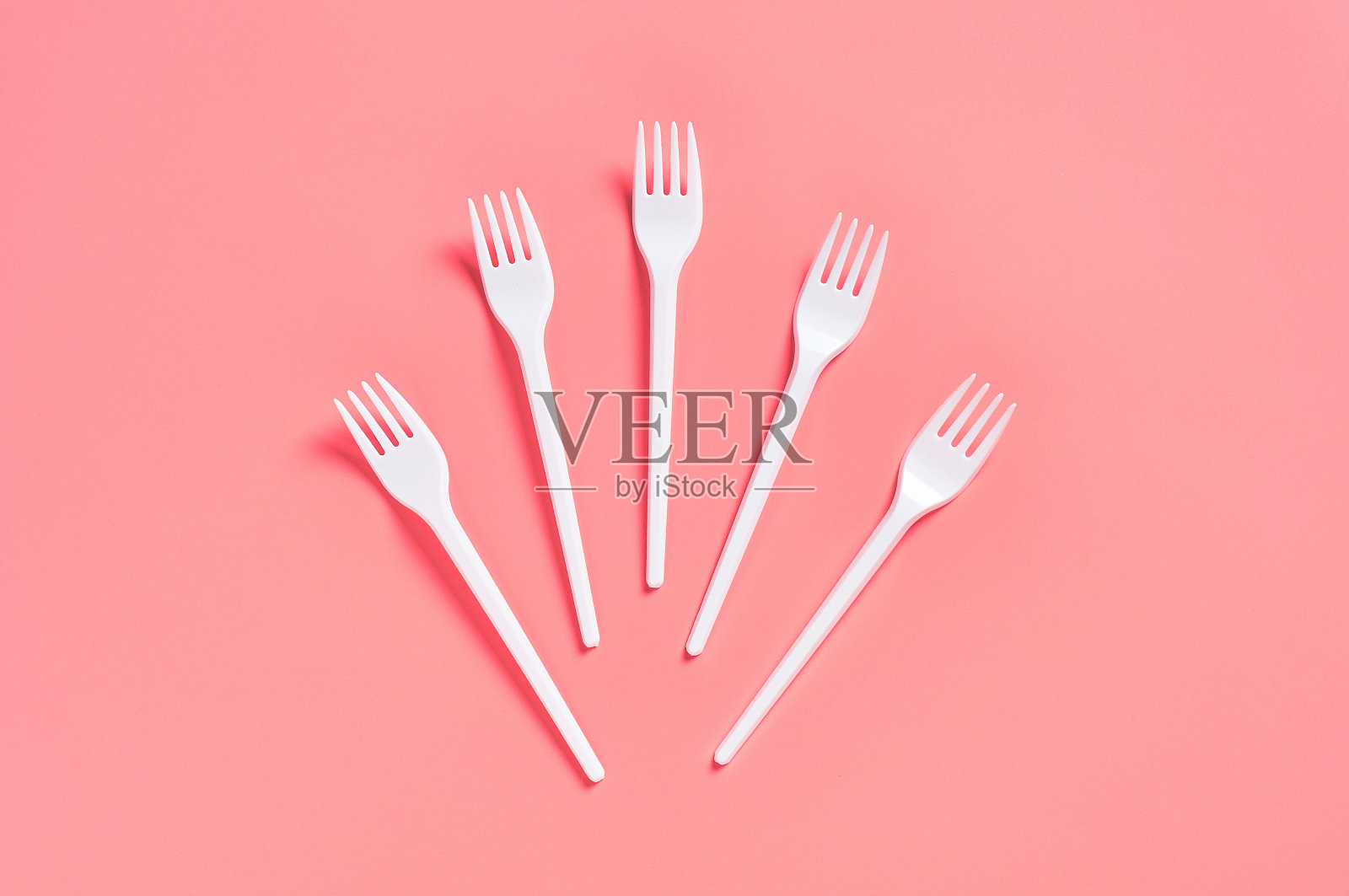 白色一次性叉子散布在粉红色的背景上。节约环境、生态、野餐、聚会等休闲活动的理念。俯视图照片摄影图片