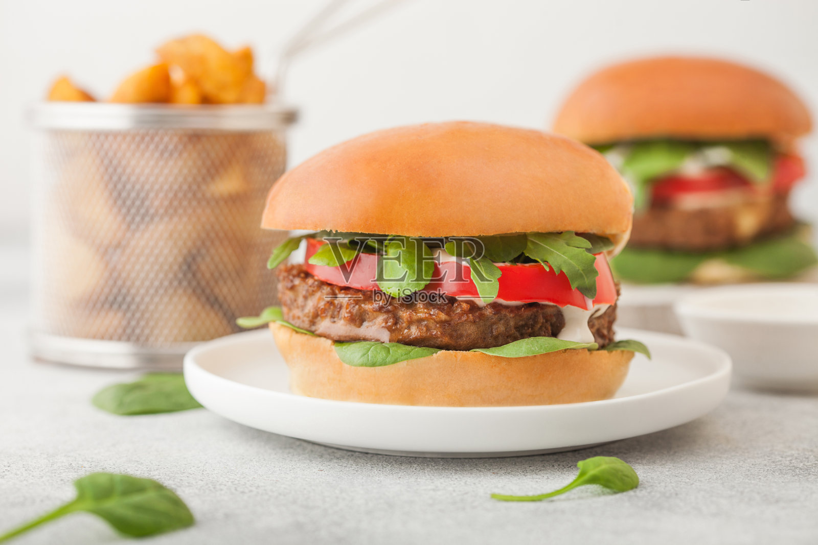 健康的素食免费汉堡在圆形陶瓷盘子，蔬菜在明亮的桌子背景土豆角。照片摄影图片