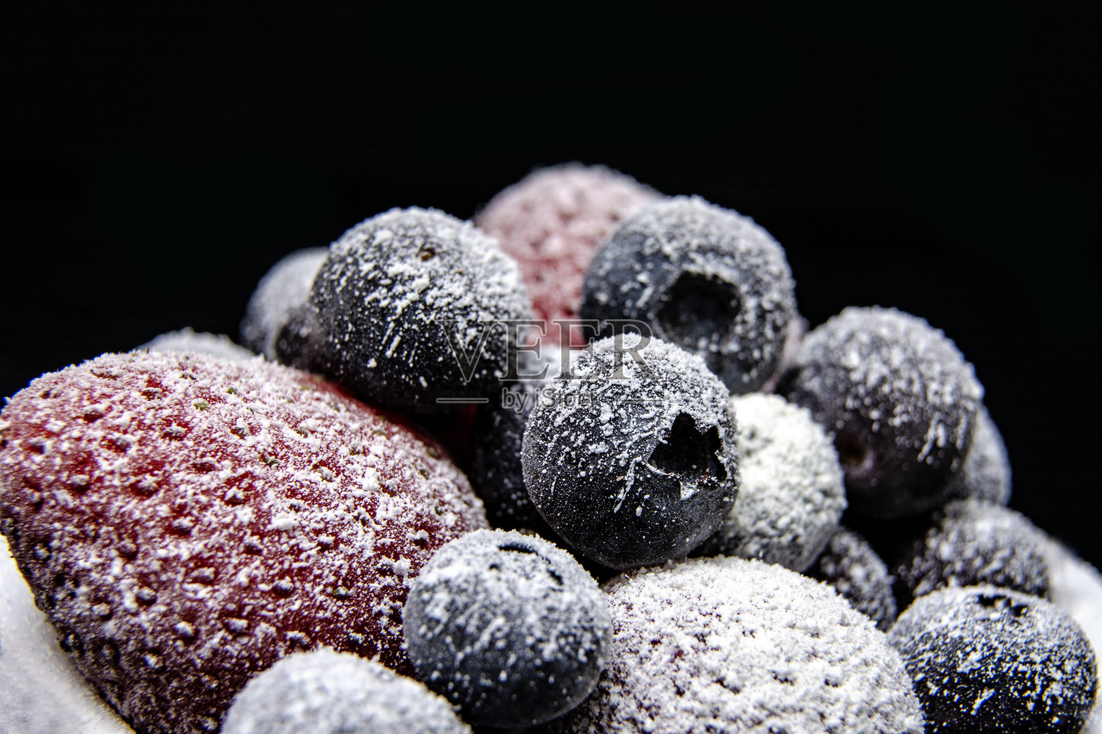 冰冻浆果的宏观视图:草莓，蓝莓在黑暗的背景照片摄影图片