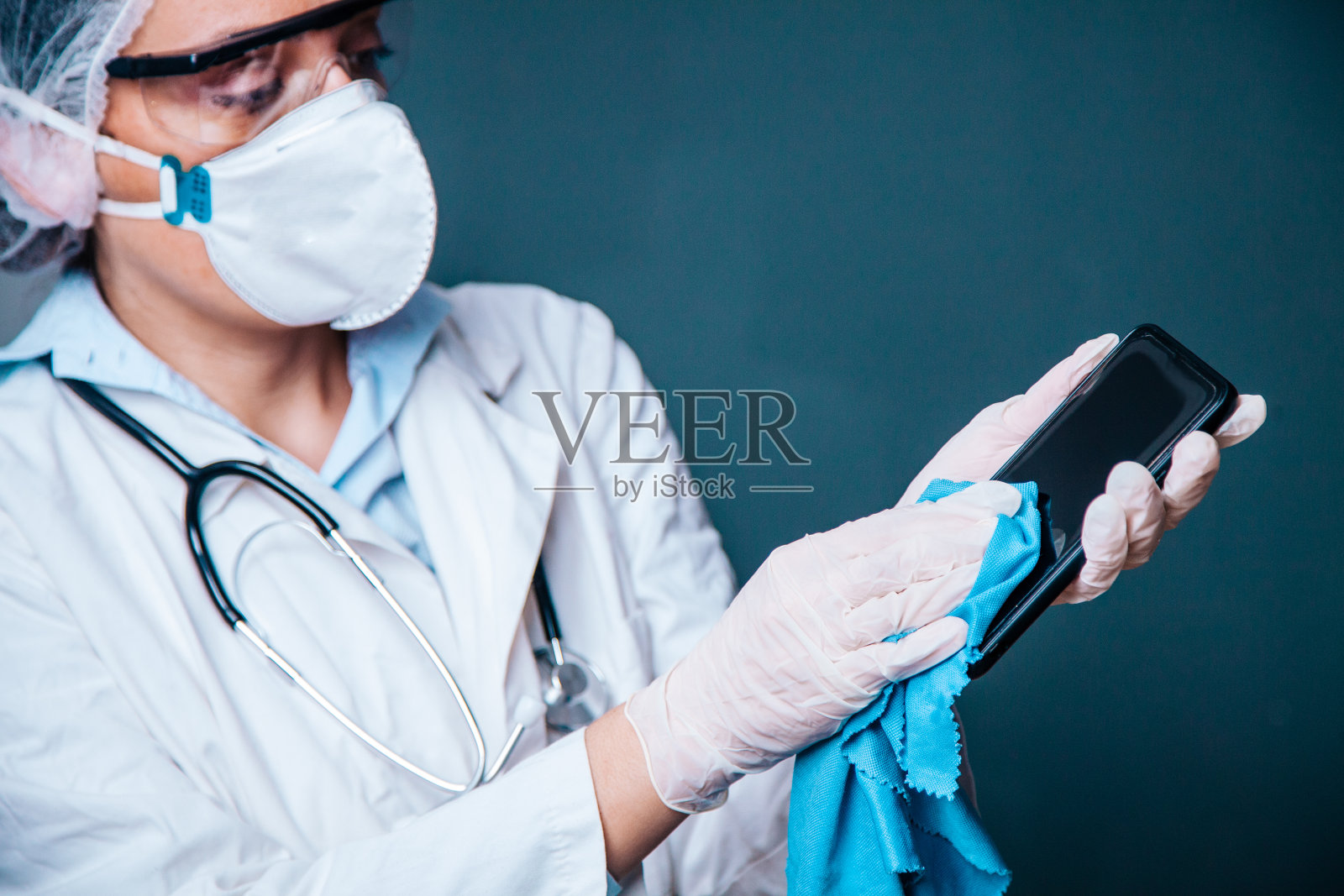 女医生用清洁凝胶清洁手机以预防COVID-19照片摄影图片