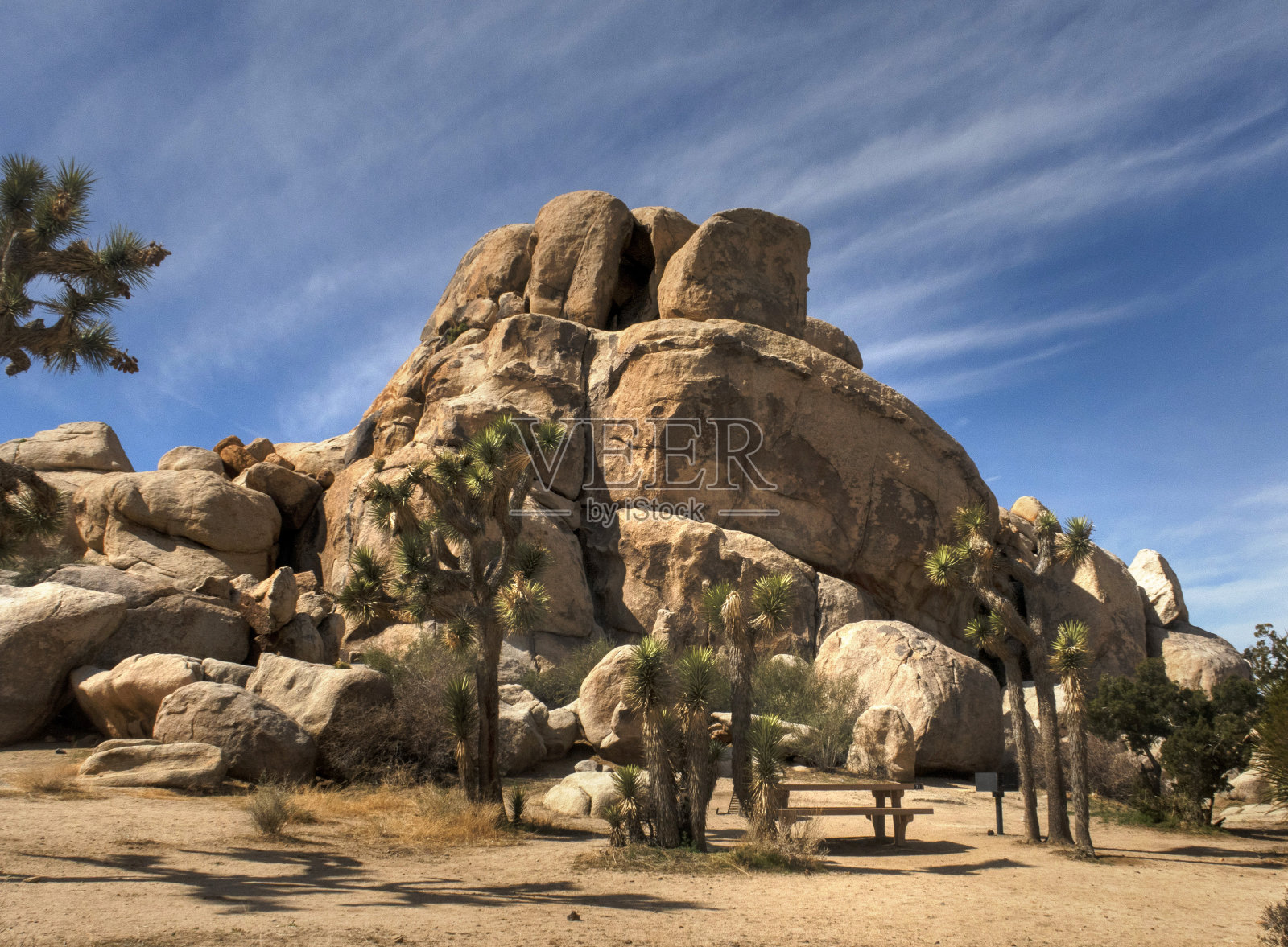 在约书亚树国家公园一个巨大的岩层前的野餐桌上照片摄影图片