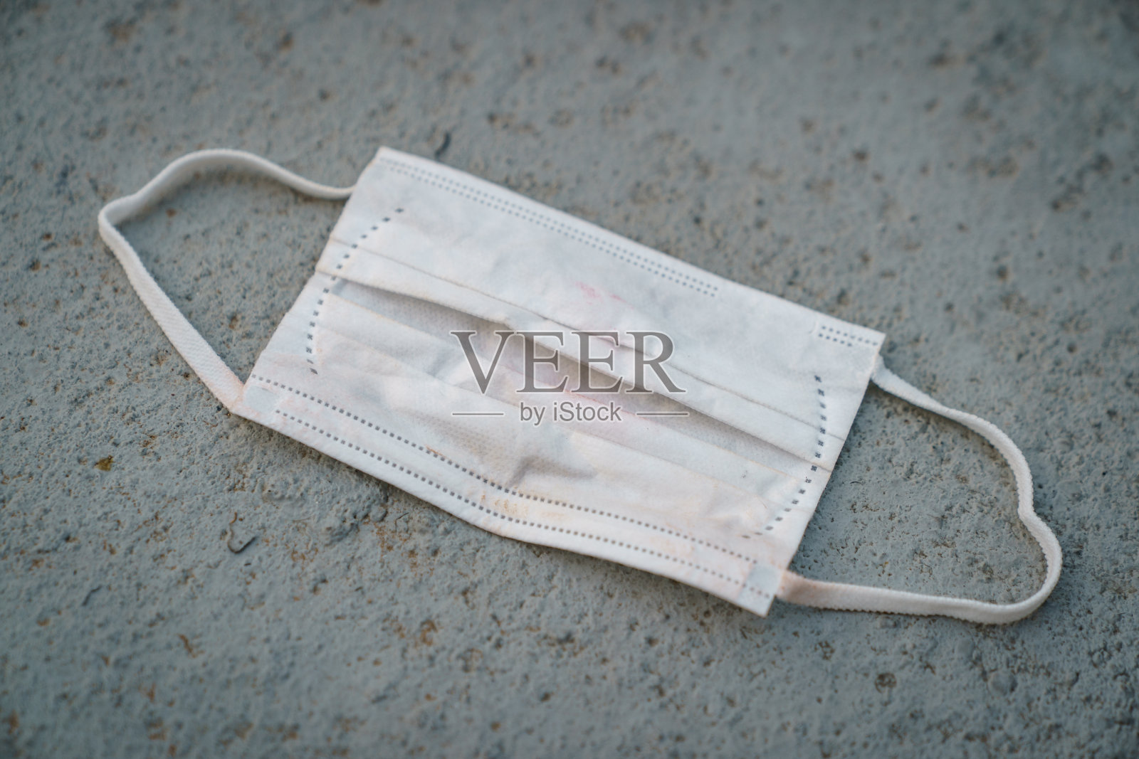 用过脏脸的外科口罩掉在地上，选择性聚焦中心口罩照片摄影图片