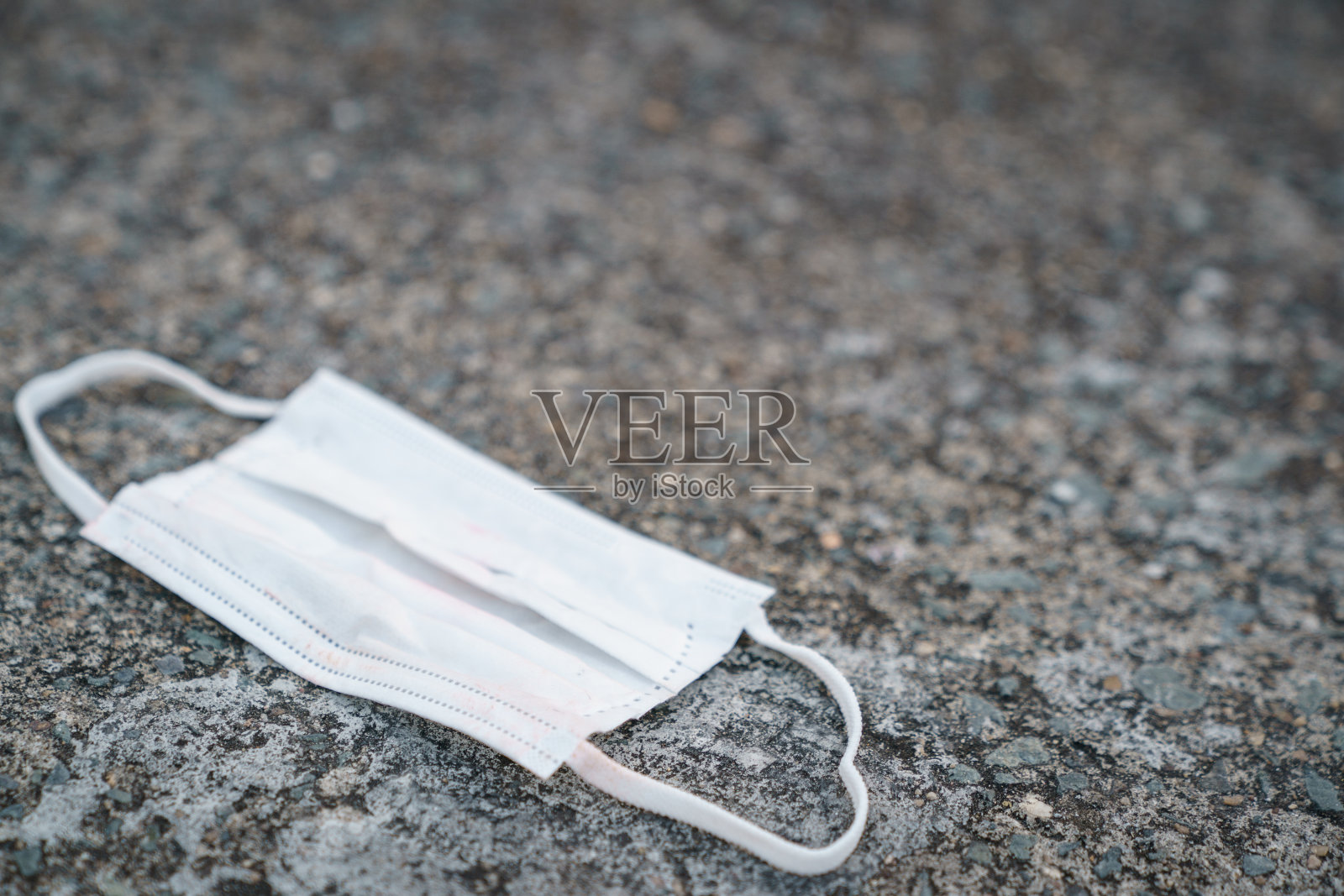 用过脏脸的外科口罩掉在地上，选择性聚焦中心口罩照片摄影图片