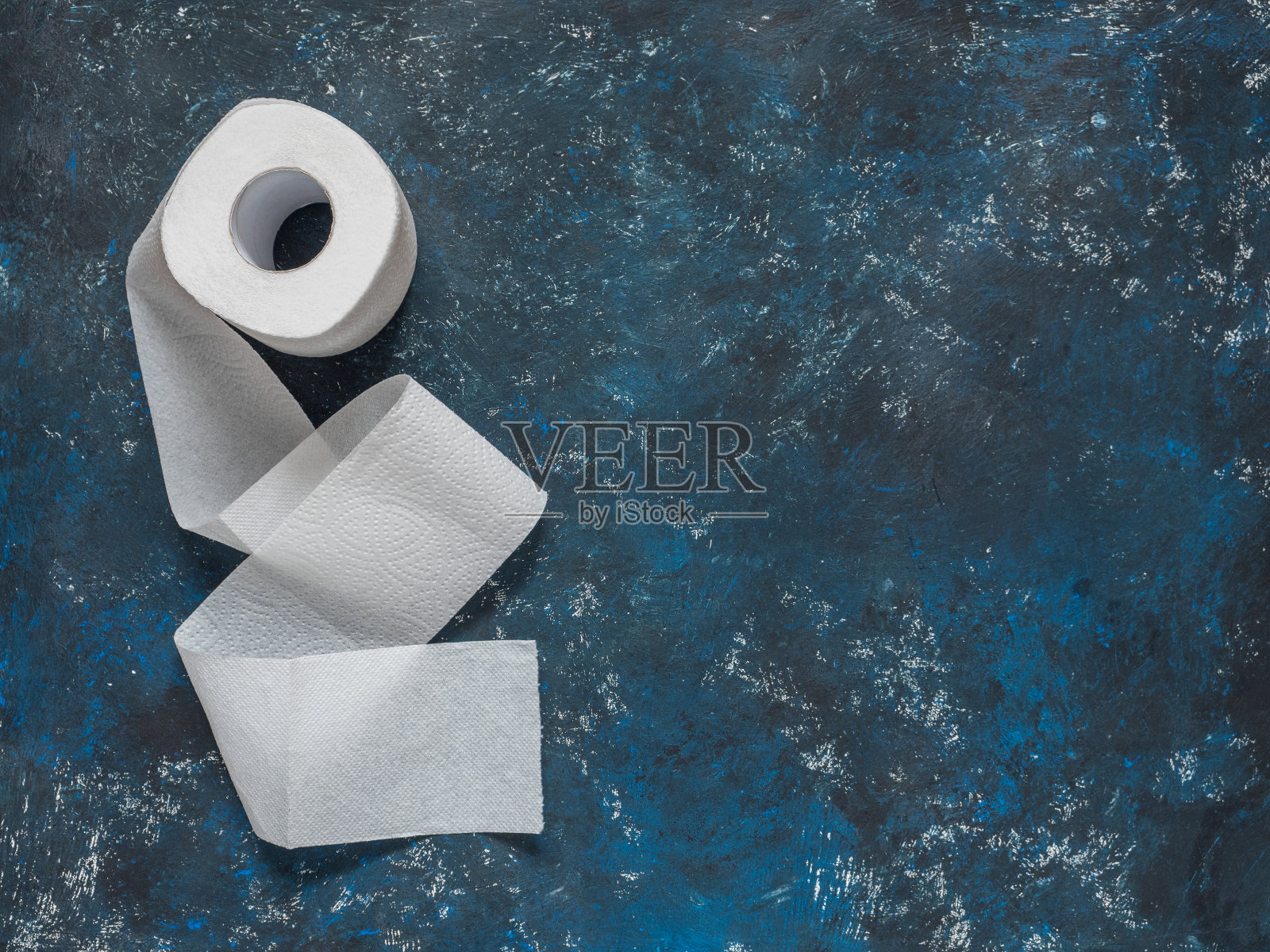 深蓝色背景的厕纸卷。俯视图，复制空间照片摄影图片