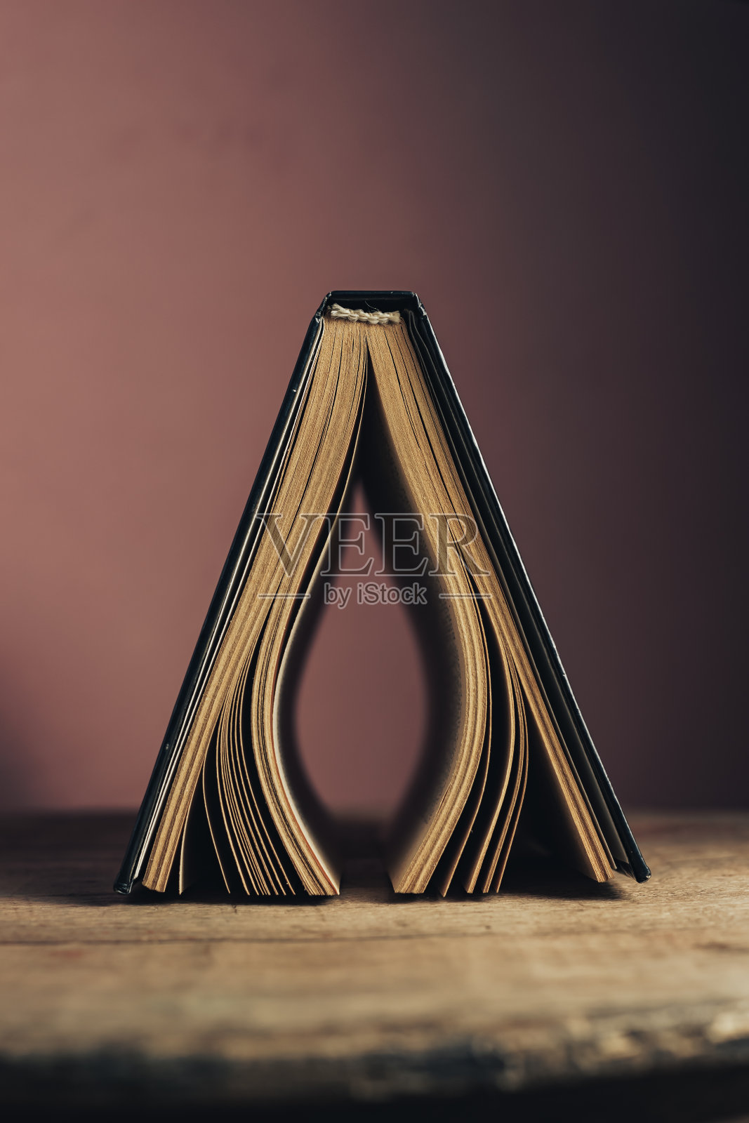 漂亮的古董古书。图案背景设计。那本书放在一张旧橡木圆木桌上，背景是红色的墙。照片摄影图片