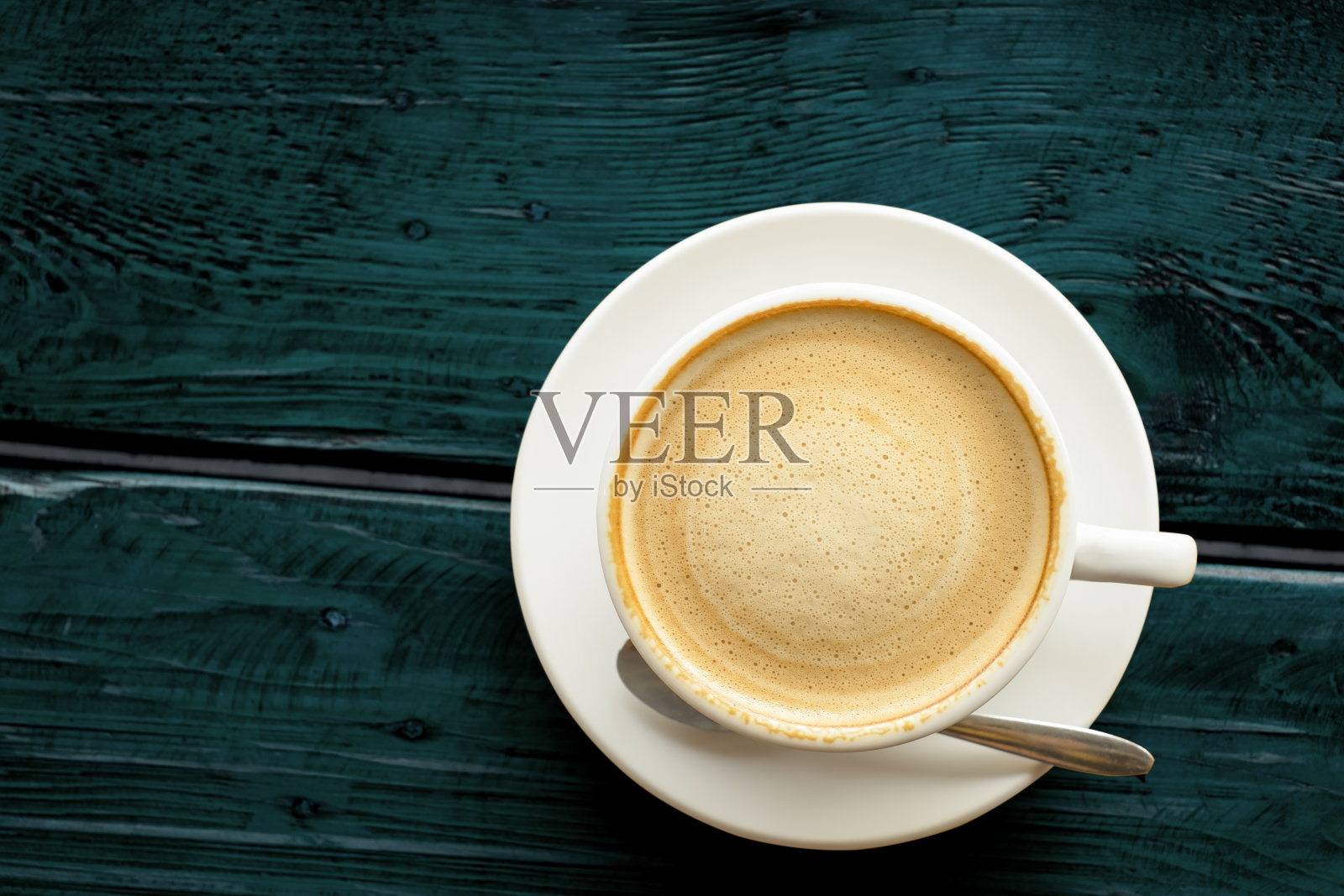 热拿铁咖啡与美丽光滑的泡沫在一个经典的白色咖啡杯设置平铺顶视图抽象图案复古的深蓝绿色木桌子背景纹理与剪切路径照片摄影图片