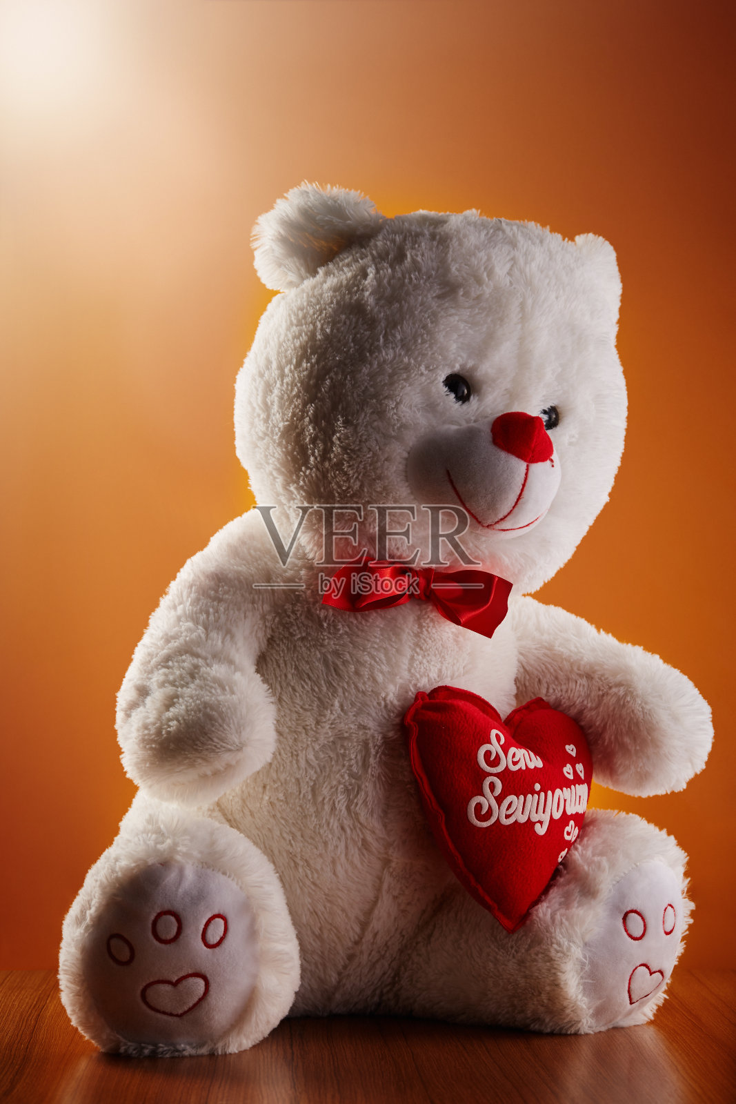 毛绒玩具泰迪熊抱着心形枕头，上面绣着“我爱你- Seni Seviyorum”的土耳其文照片摄影图片