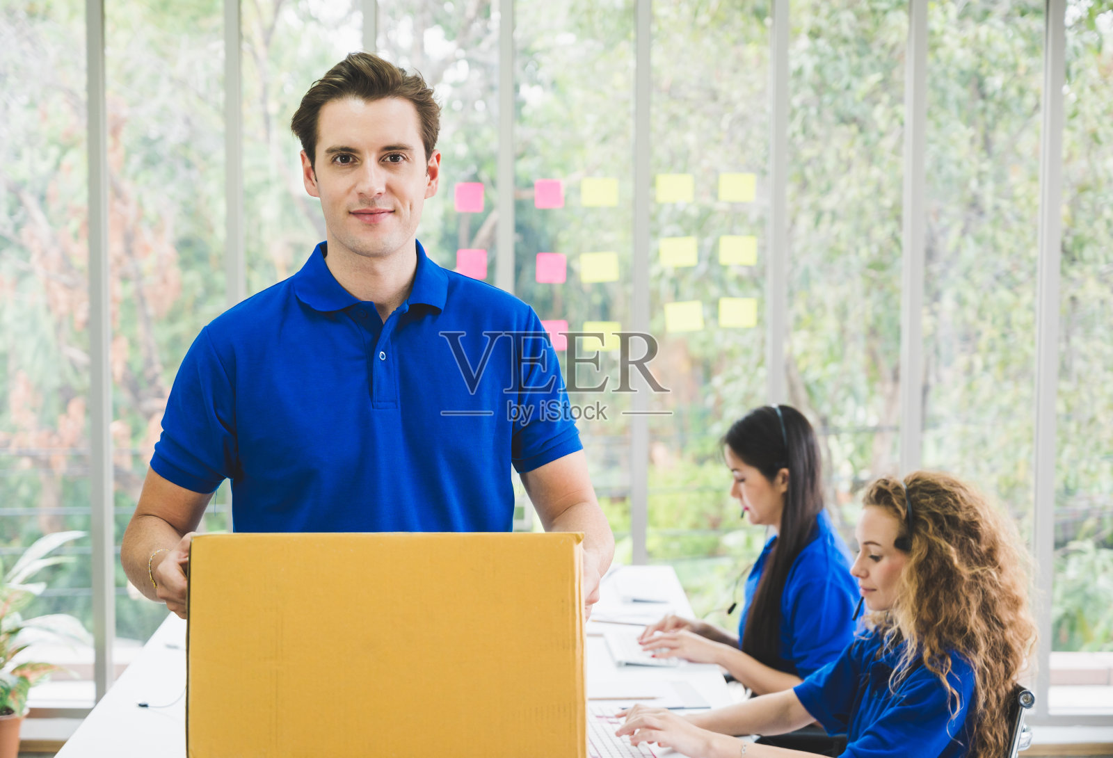 手持包裹纸箱的年轻英俊的快递员在配送中心照片摄影图片