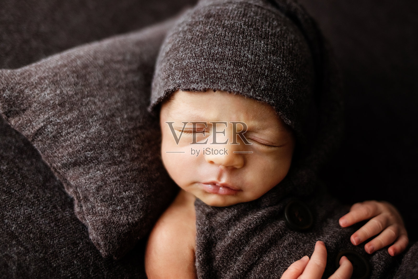 可爱的新生婴儿在棕色毯子上，深色背景。婴儿用品包装模板，育儿，医疗健康概念照片摄影图片