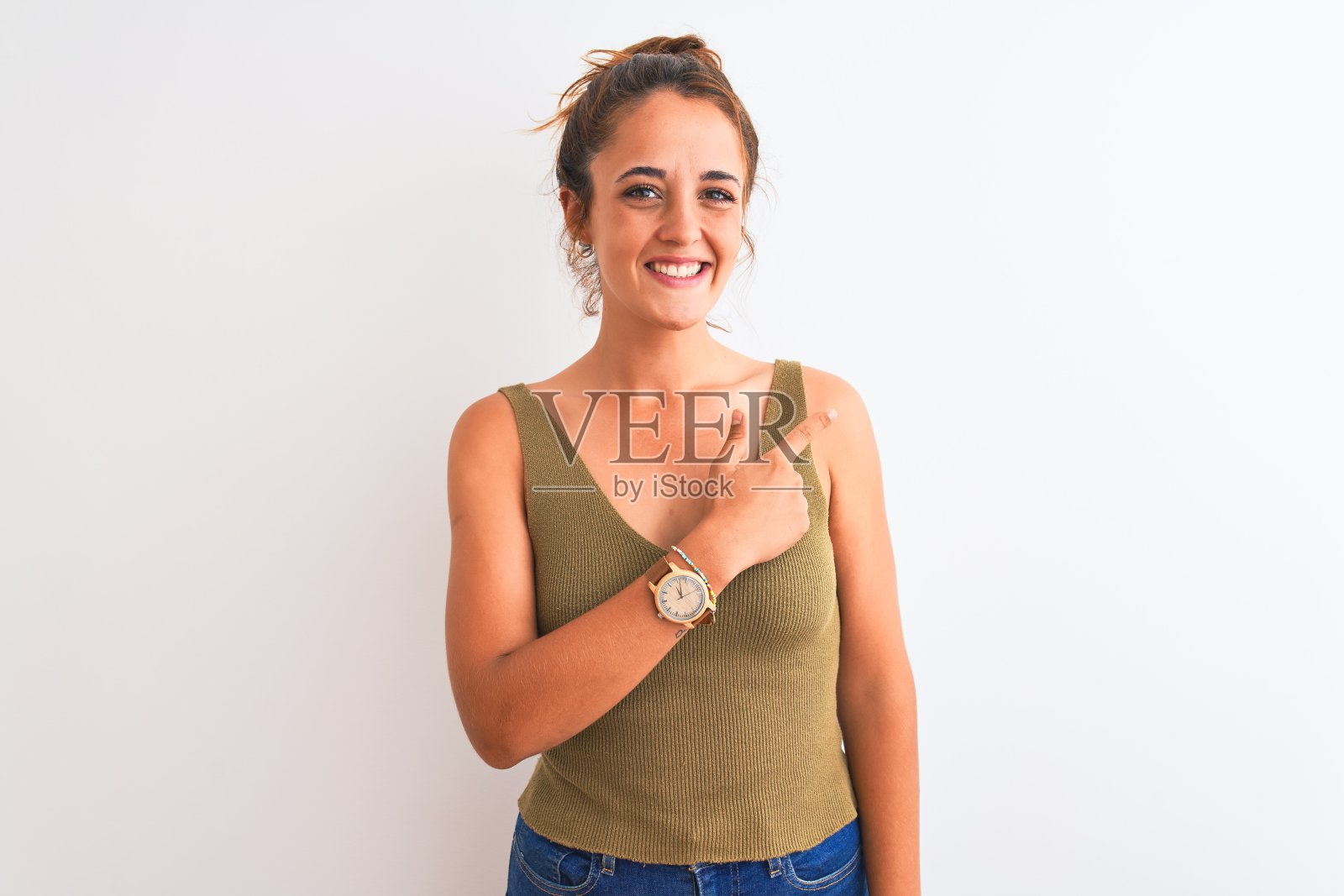 年轻的红发女子挽着一个发髻，在孤立的背景下，面带微笑，手和手指向上指向一边，脸上洋溢着快乐和自然的表情照片摄影图片