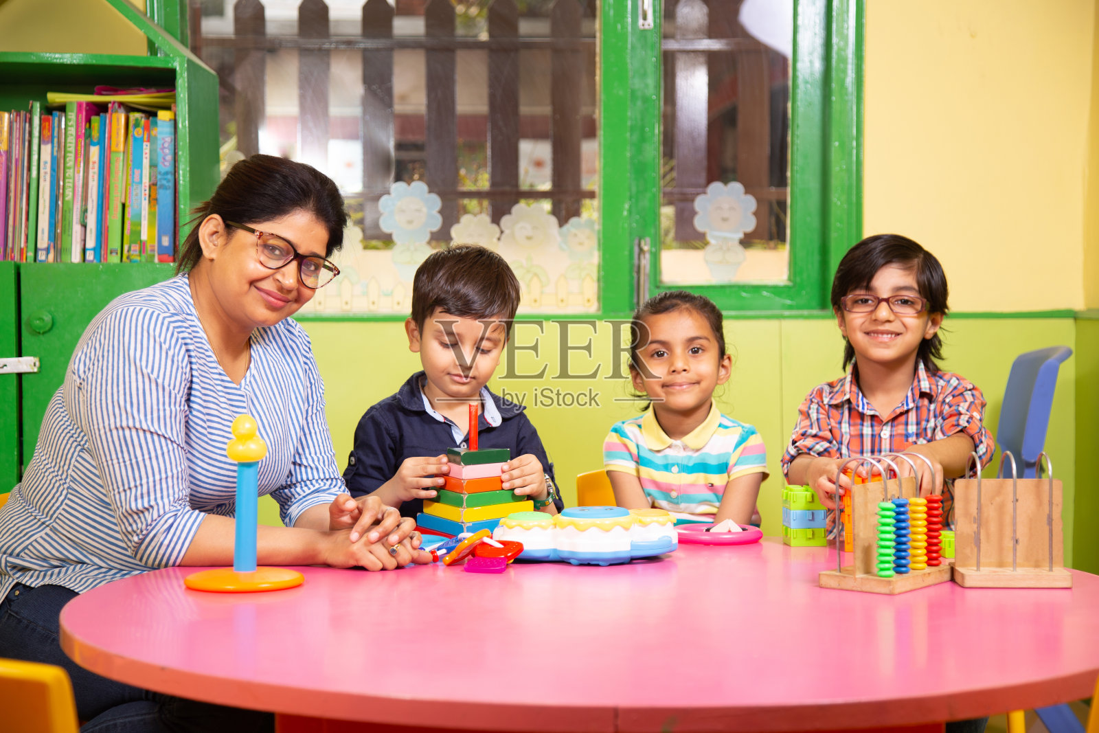 老师教导学龄前儿童搭积木照片摄影图片