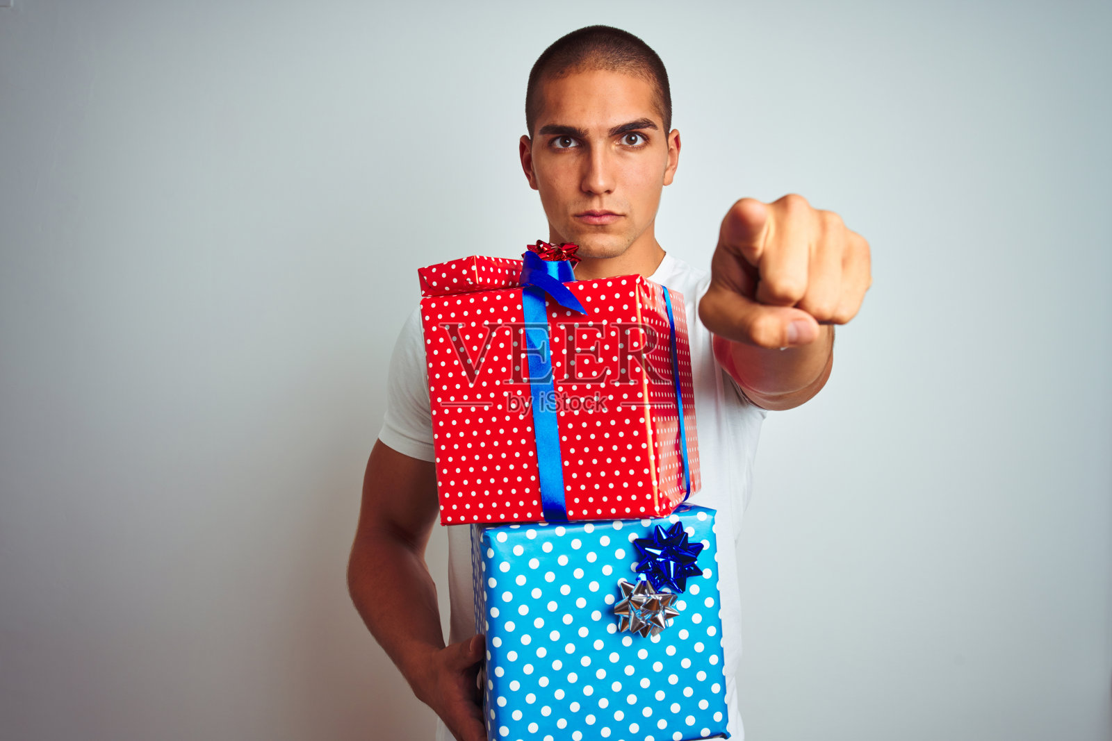 年轻英俊的男人拿着生日礼物在白色孤立的背景指向指向相机和你，手势，积极和自信的手势从前面照片摄影图片