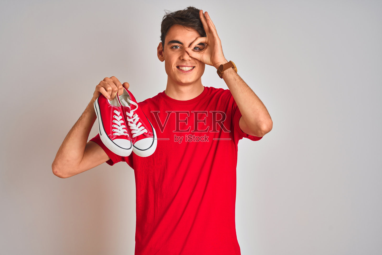 少年展示时尚休闲运动鞋，红色背景照片摄影图片