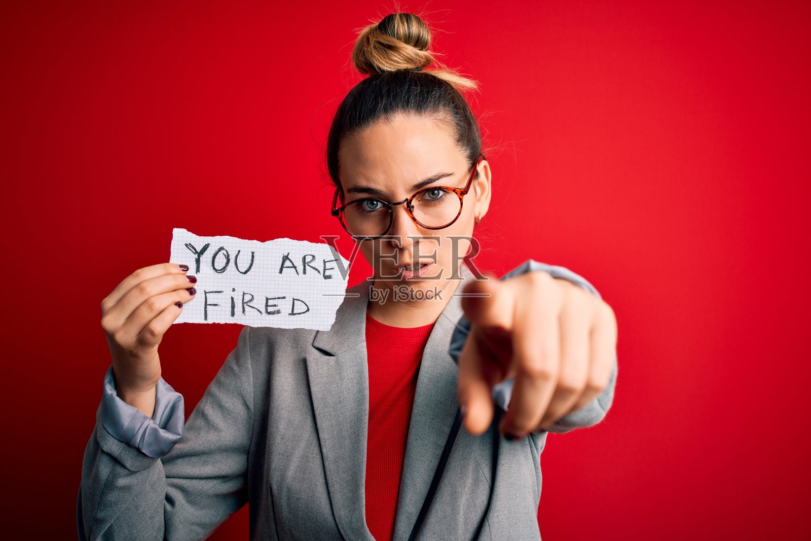 年轻漂亮的金发碧眼的女人拿着纸和你一起被解雇的信息手指对着摄像机和你，手势，正面自信的手势照片摄影图片