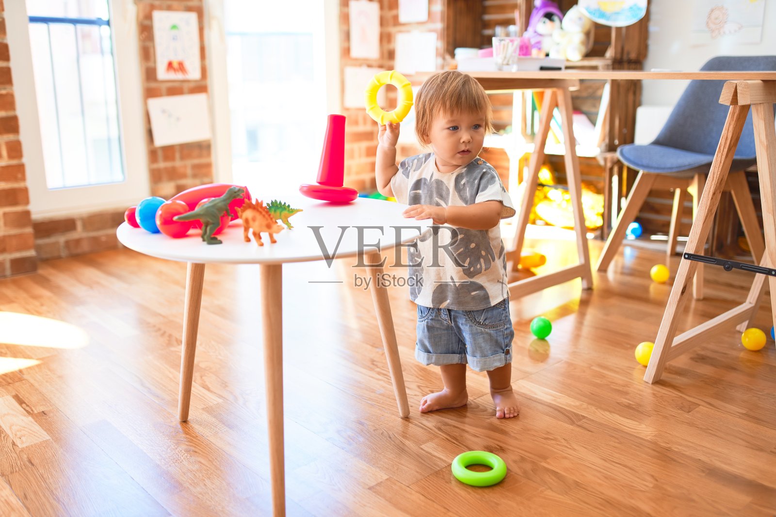 萌萌的幼童在幼儿园里用圆环围着许多玩具堆成金字塔照片摄影图片